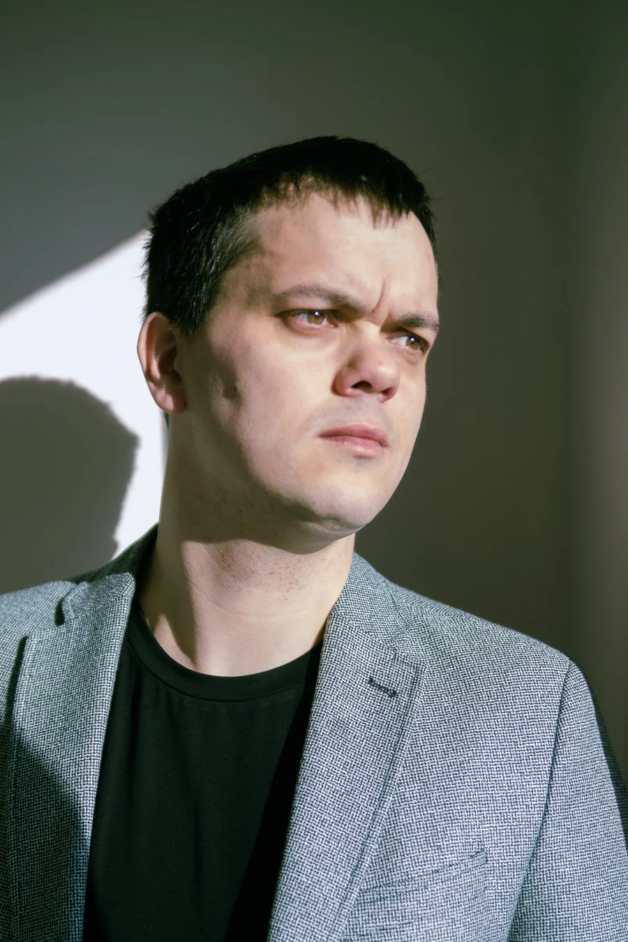 Portret mężczyzny na jasnym tle — fotografia z naciskiem na kontrast, cień i minimalistyczny styl, Konstancin