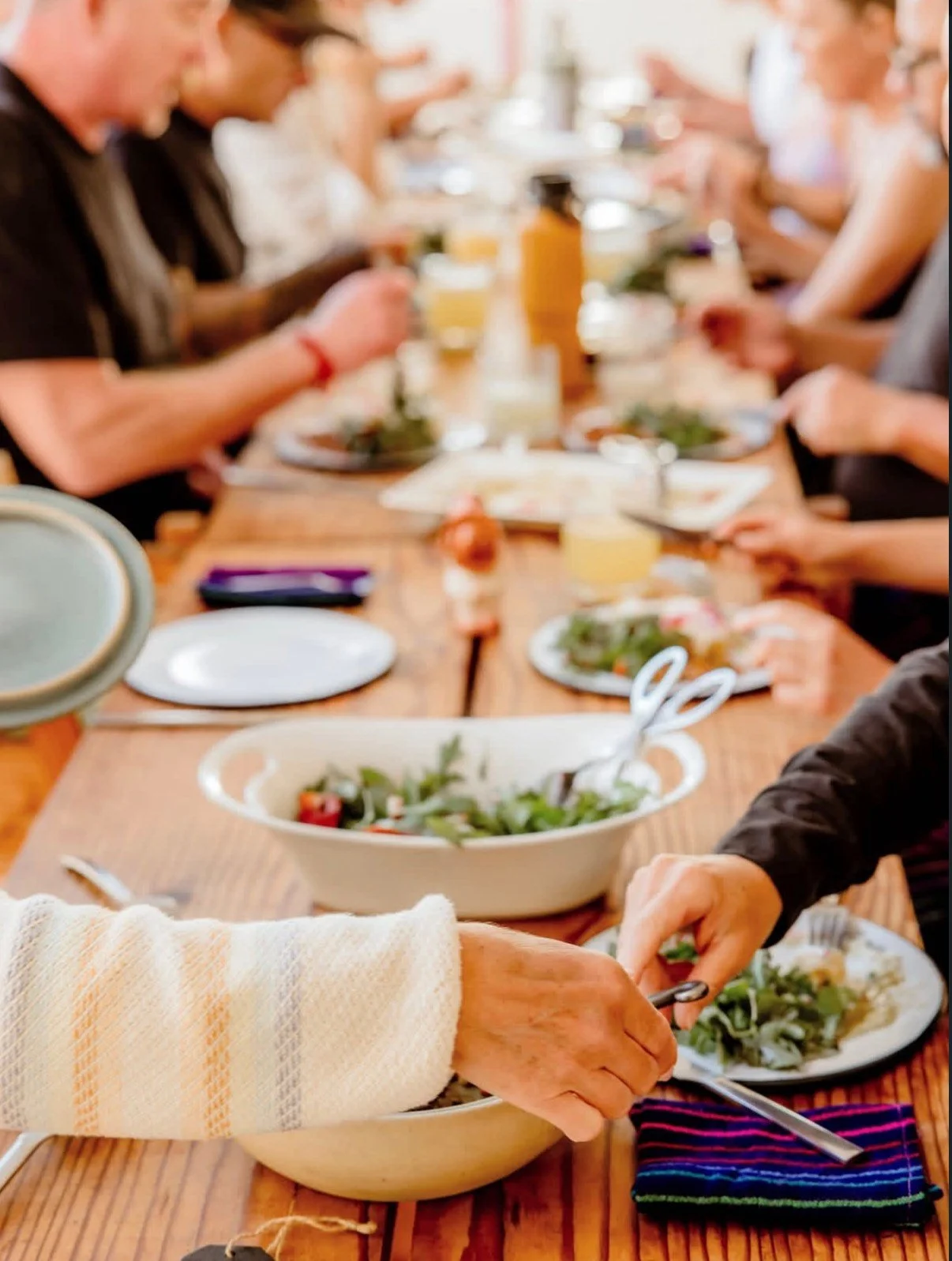 a group of people sit around a long table and eat a meal