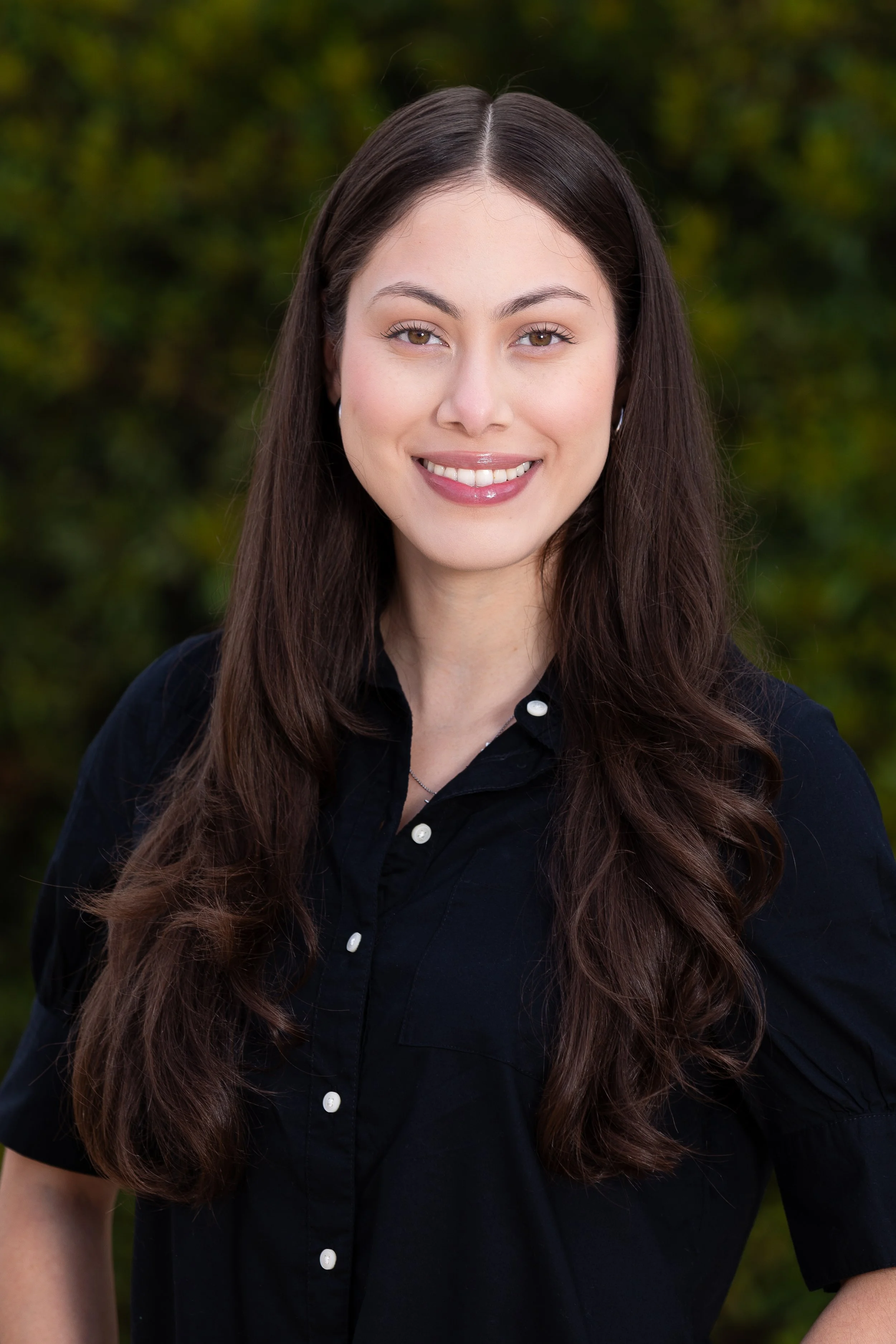 Photography of Stephanie Alquicira, head and shoulders in front of dark leafy background