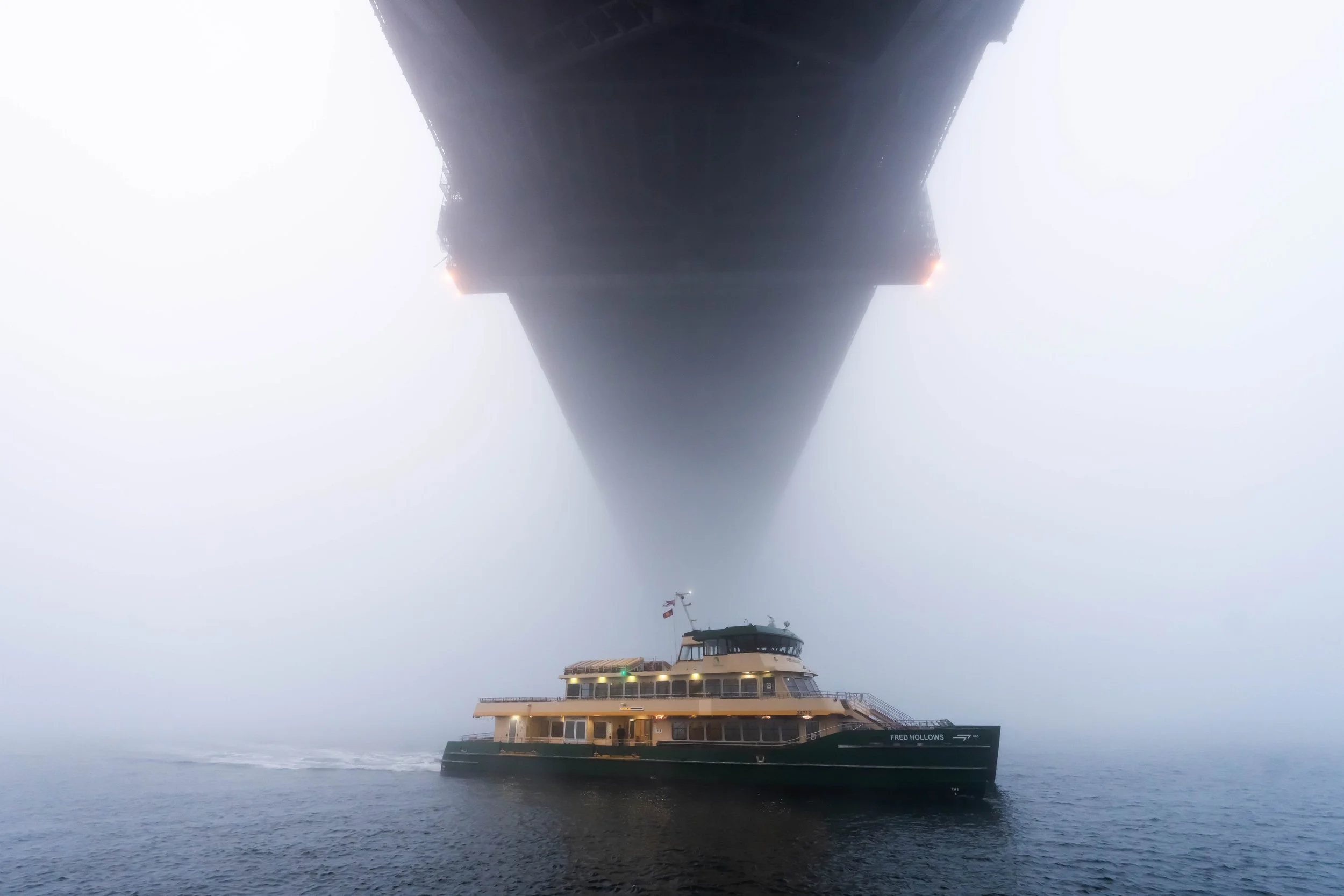 A Sydney ferry travels under the Sydney Harbour Bridge in heavy fog
