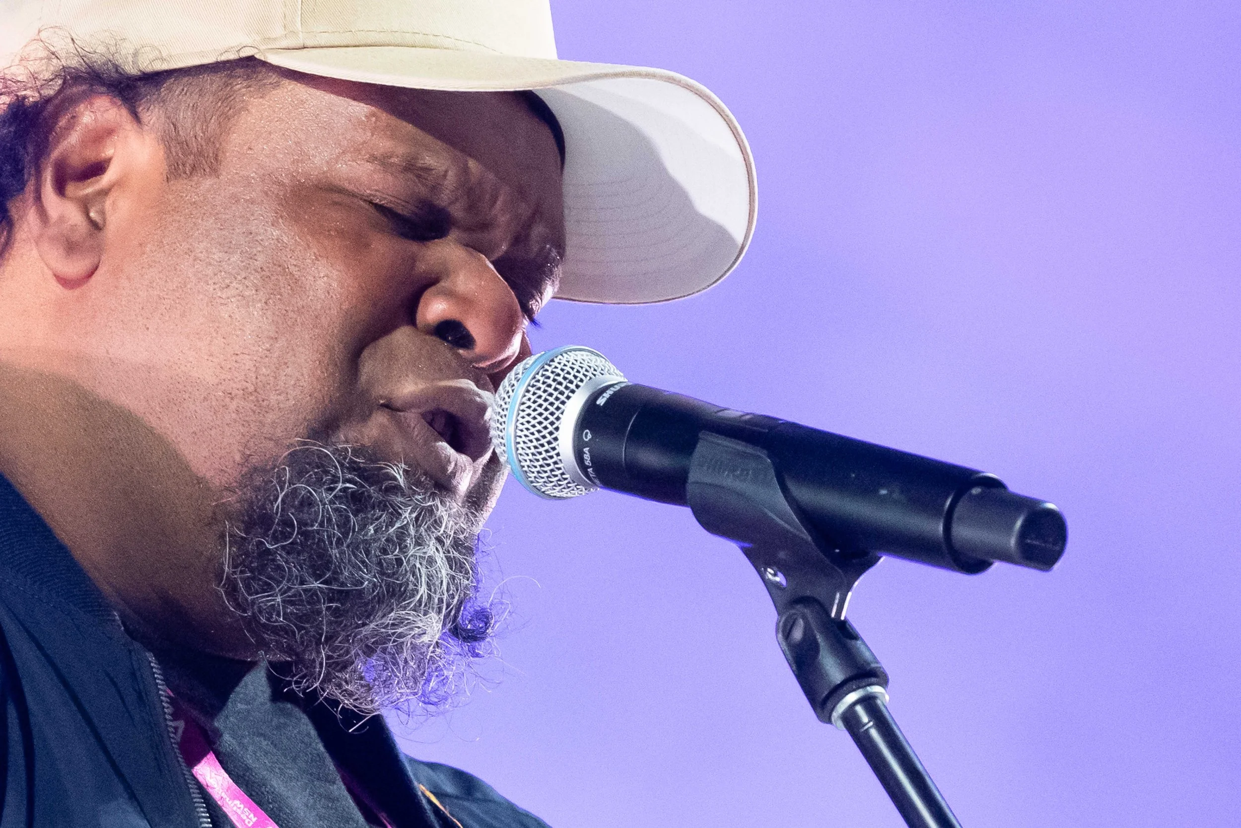 A singer on stage with a microphone and a purple background