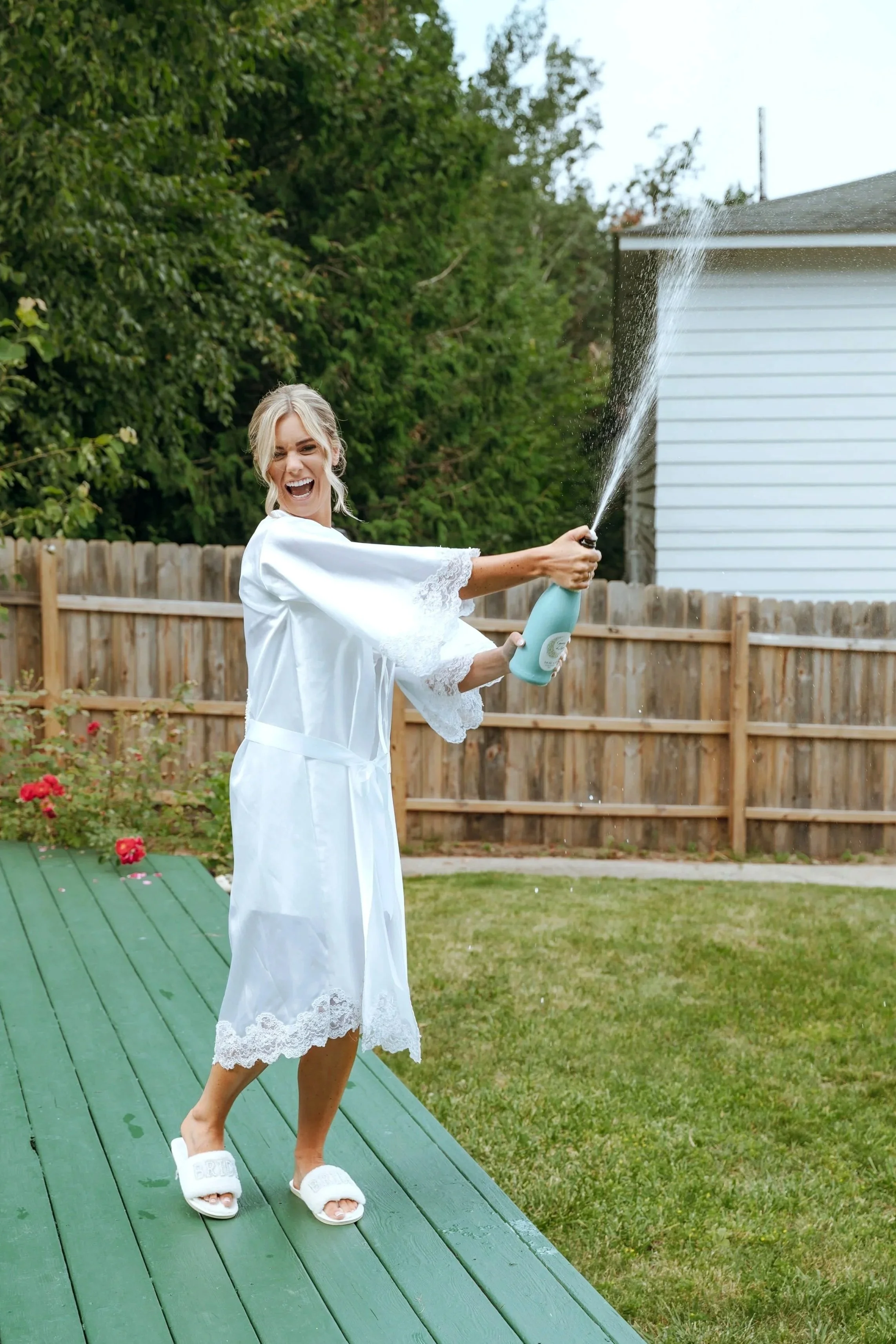 Sydney pops champagne outside during her wedding morning in Petoskey, Michigan.