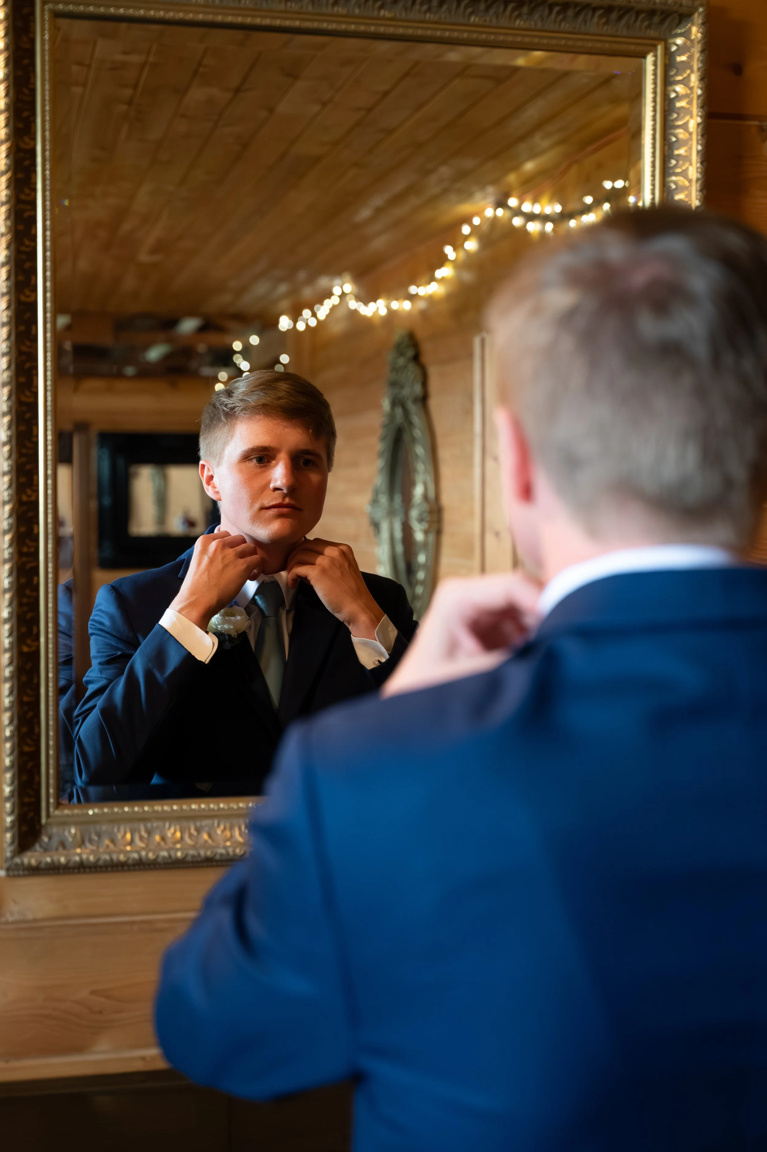 Matt adjusts his tie in the mirror while getting ready for his wedding at Gypsy Distillery.