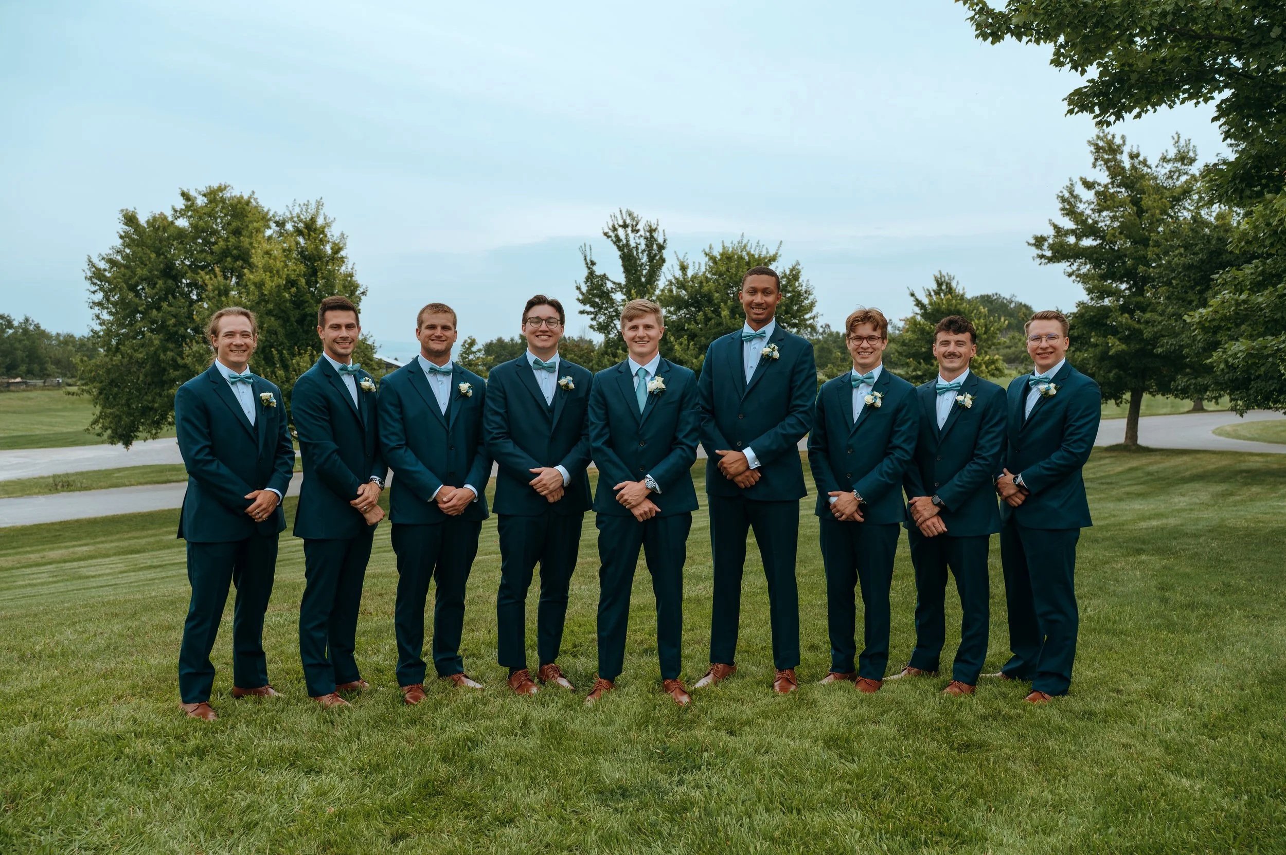 Matt stands with his groomsmen in navy suits outside Gypsy Distillery in Petoskey, Michigan.