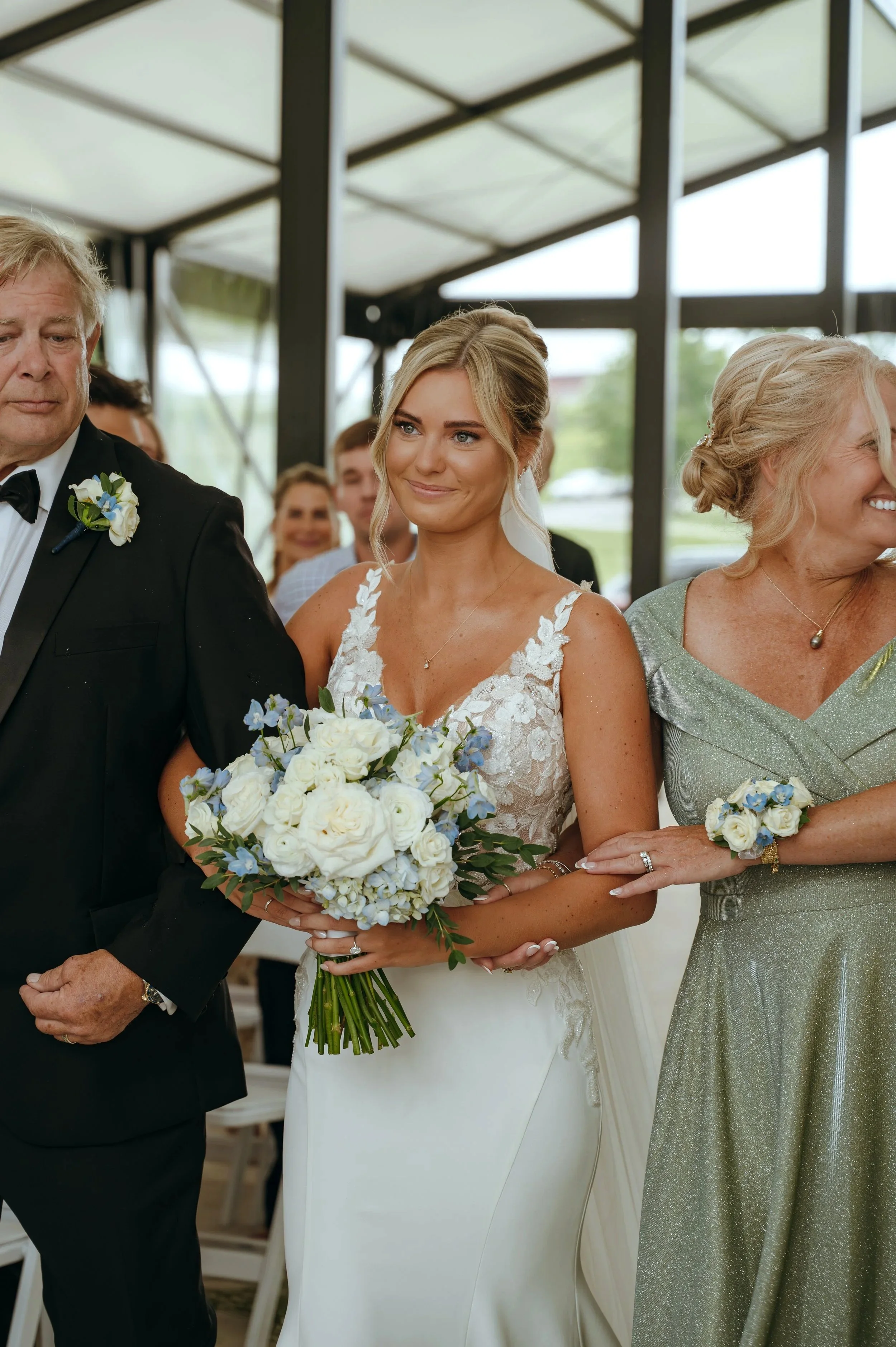 Sydney walks down the aisle with her parents during her wedding ceremony in Petoskey, Michigan.