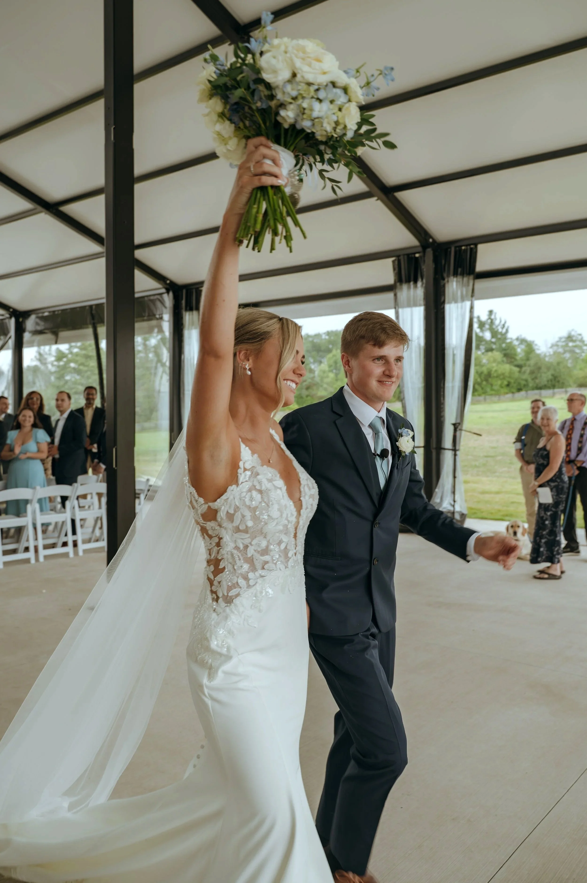 Sydney raises her bouquet while celebrating with Matt after their wedding ceremony in Petoskey, Michigan.