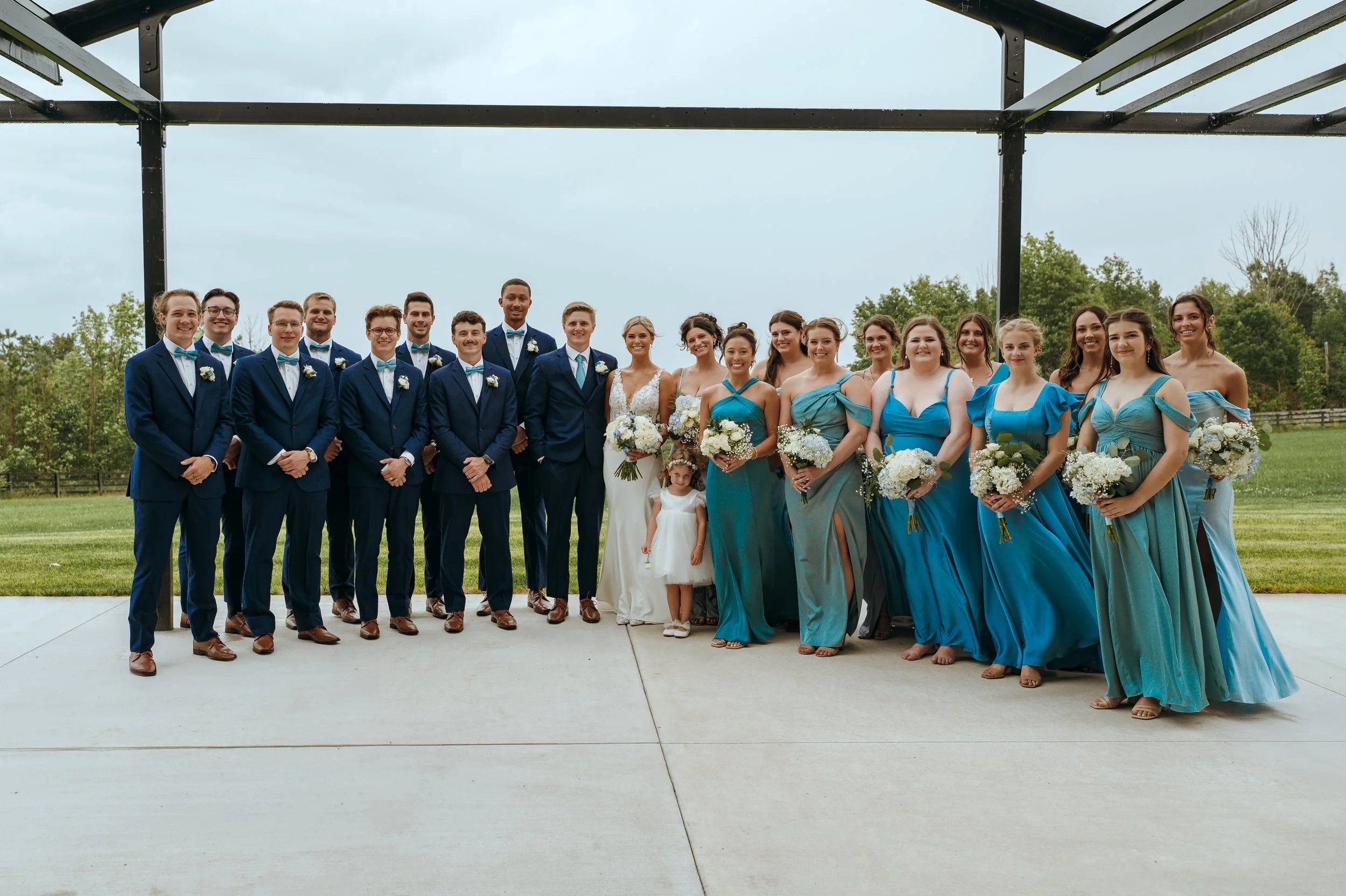 Sydney and Matt stand with their full wedding party outside Gypsy Distillery in Petoskey, Michigan.