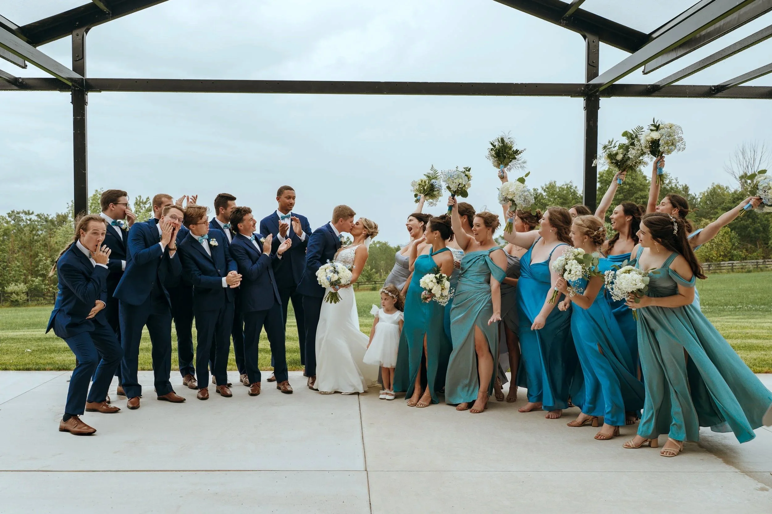 Sydney and Matt laugh with their wedding party during playful portraits outside Gypsy Distillery.