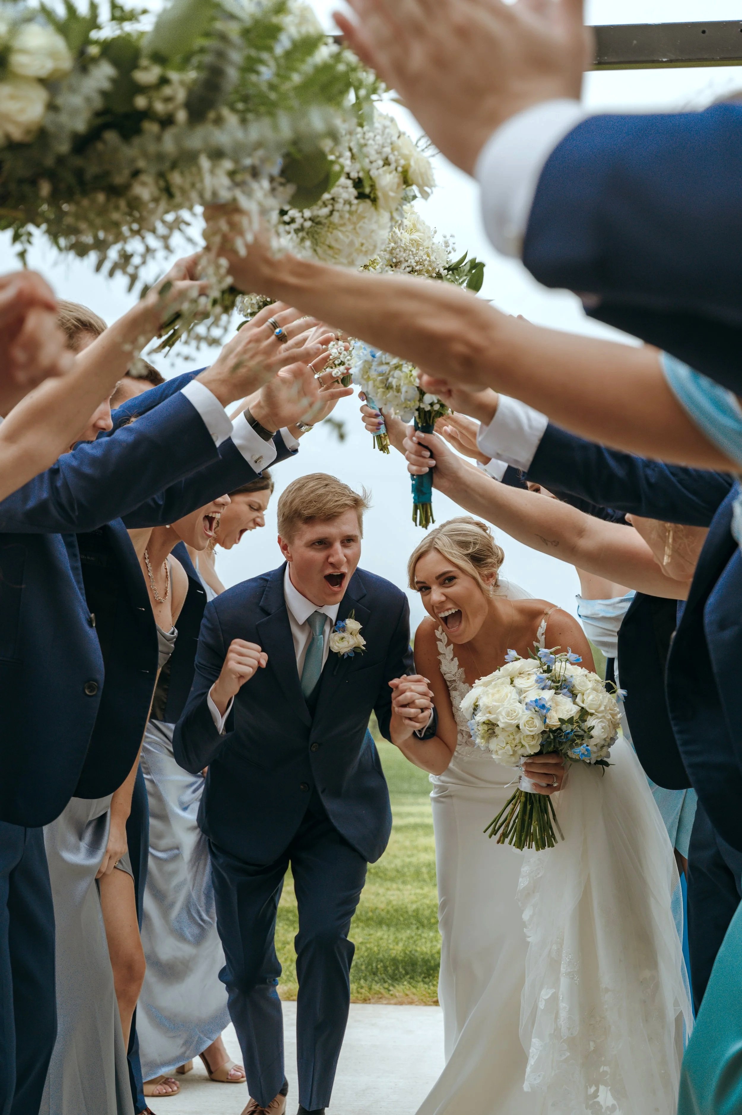 Sydney and Matt run through a tunnel created by their wedding party after their Petoskey ceremony.