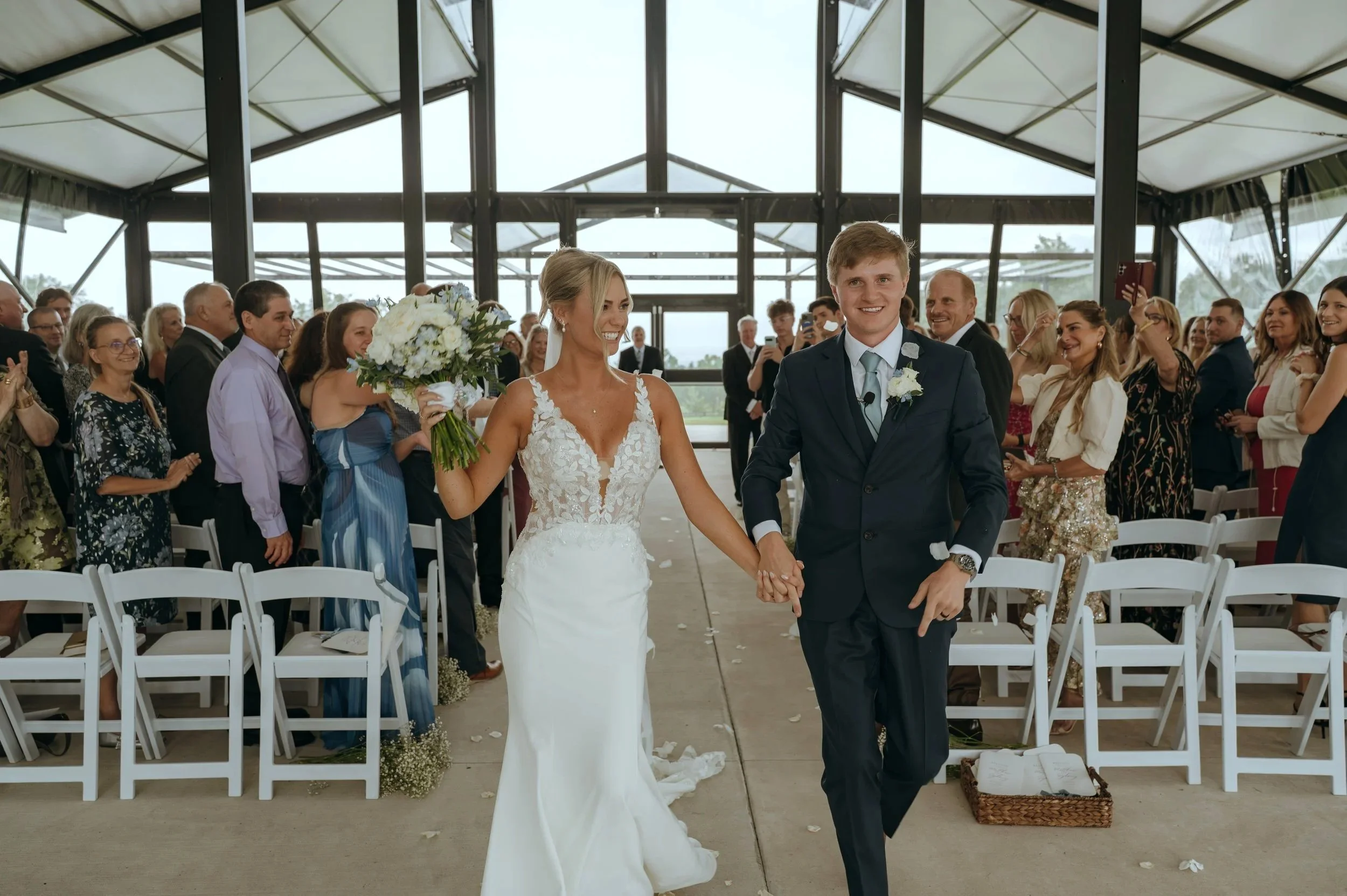Sydney and Matt smile as they walk back up the aisle after their wedding ceremony at Gypsy Distillery in Petoskey, Michigan.