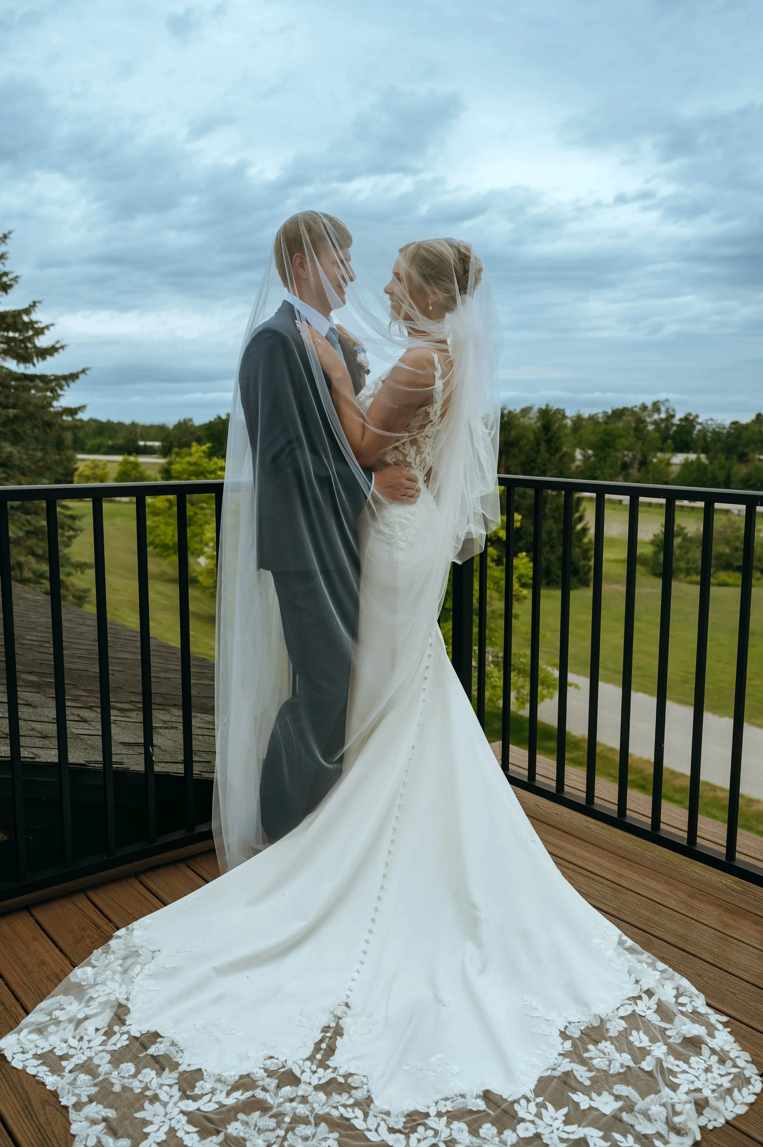 Sydney and Matt stand together on the rooftop at Gypsy Distillery during their Petoskey wedding.