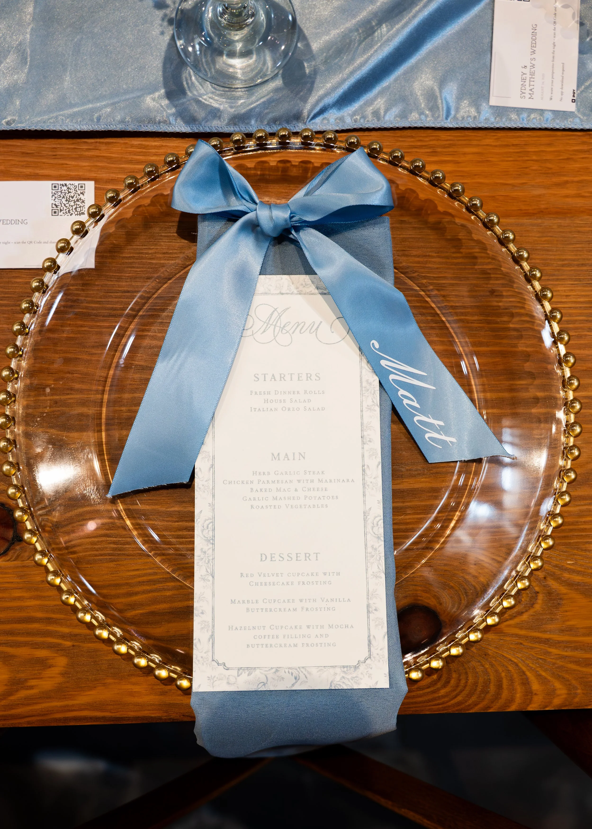 Wedding place setting with a blue ribbon and menu at Gypsy Distillery in Petoskey, Michigan.