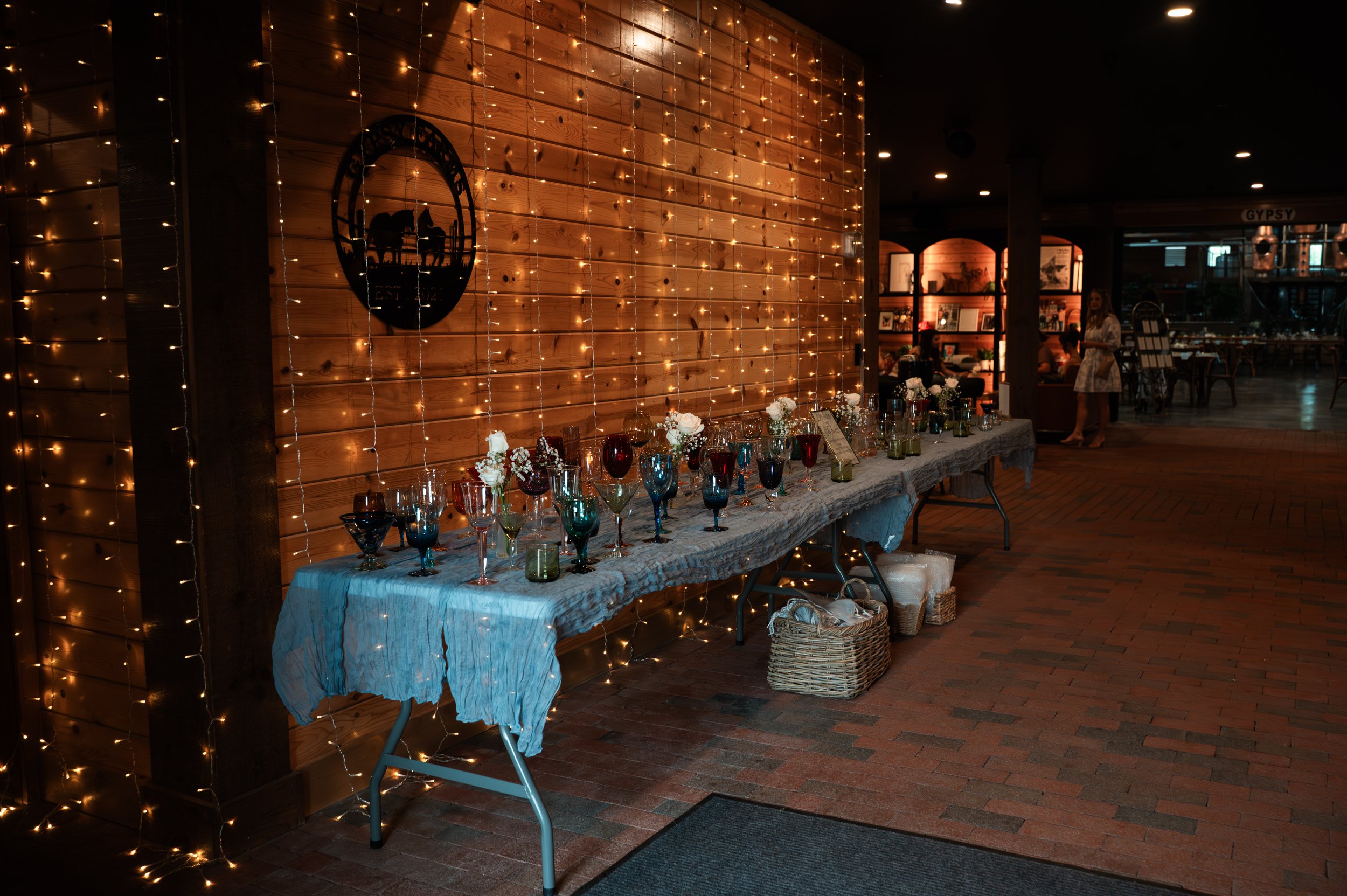 A collection of handpicked vintage glasses displayed as wedding favors at Sydney and Matt’s Gypsy Distillery wedding.