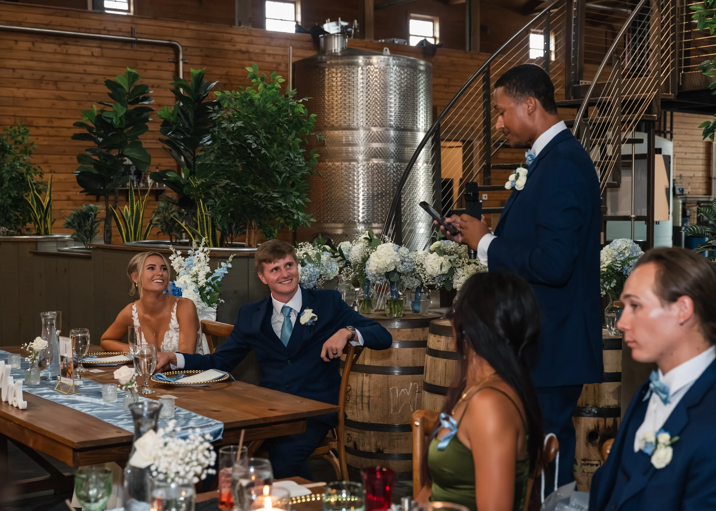 Sydney and Matt listen as a guest gives a toast during their Gypsy Distillery wedding reception.