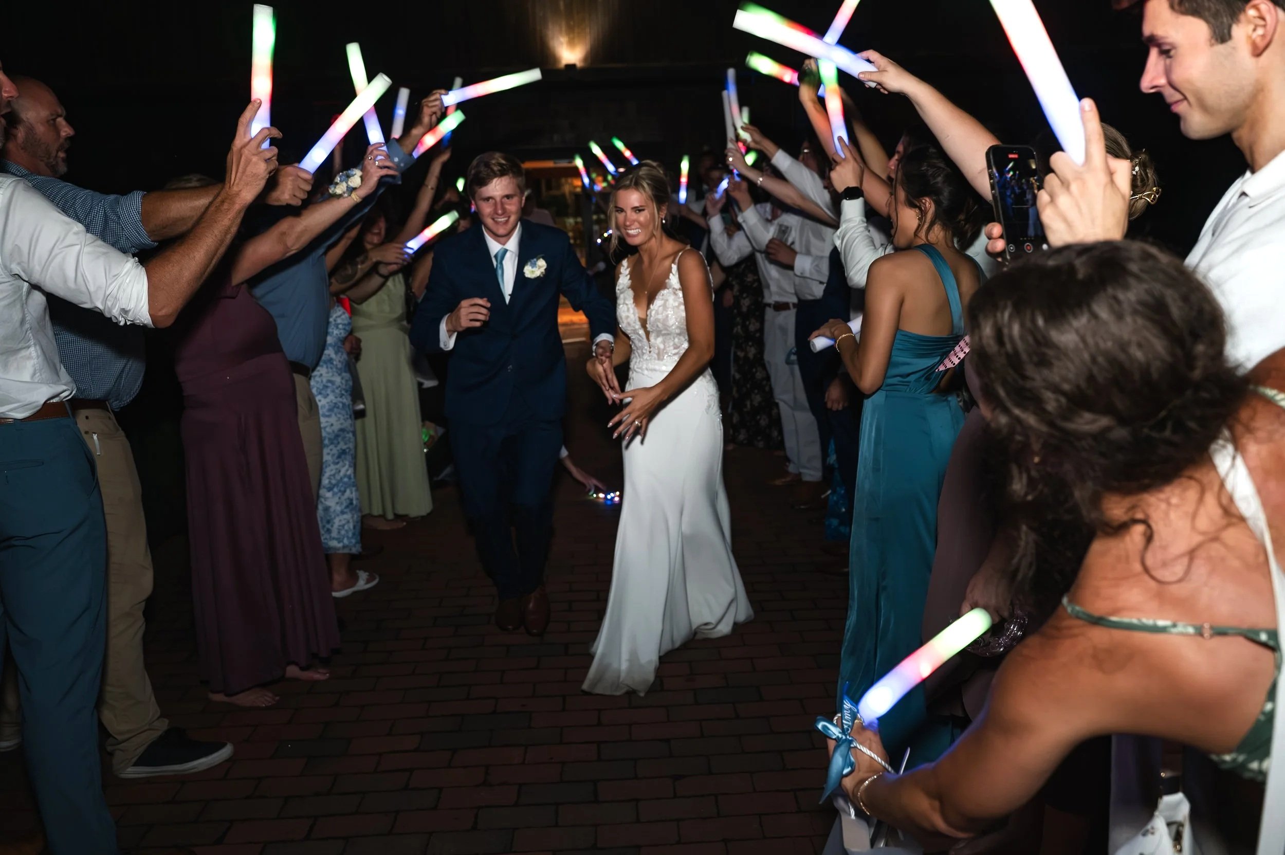 Wedding guests cheer as Sydney and Matt celebrate during their glow-stick exit at Gypsy Distillery.