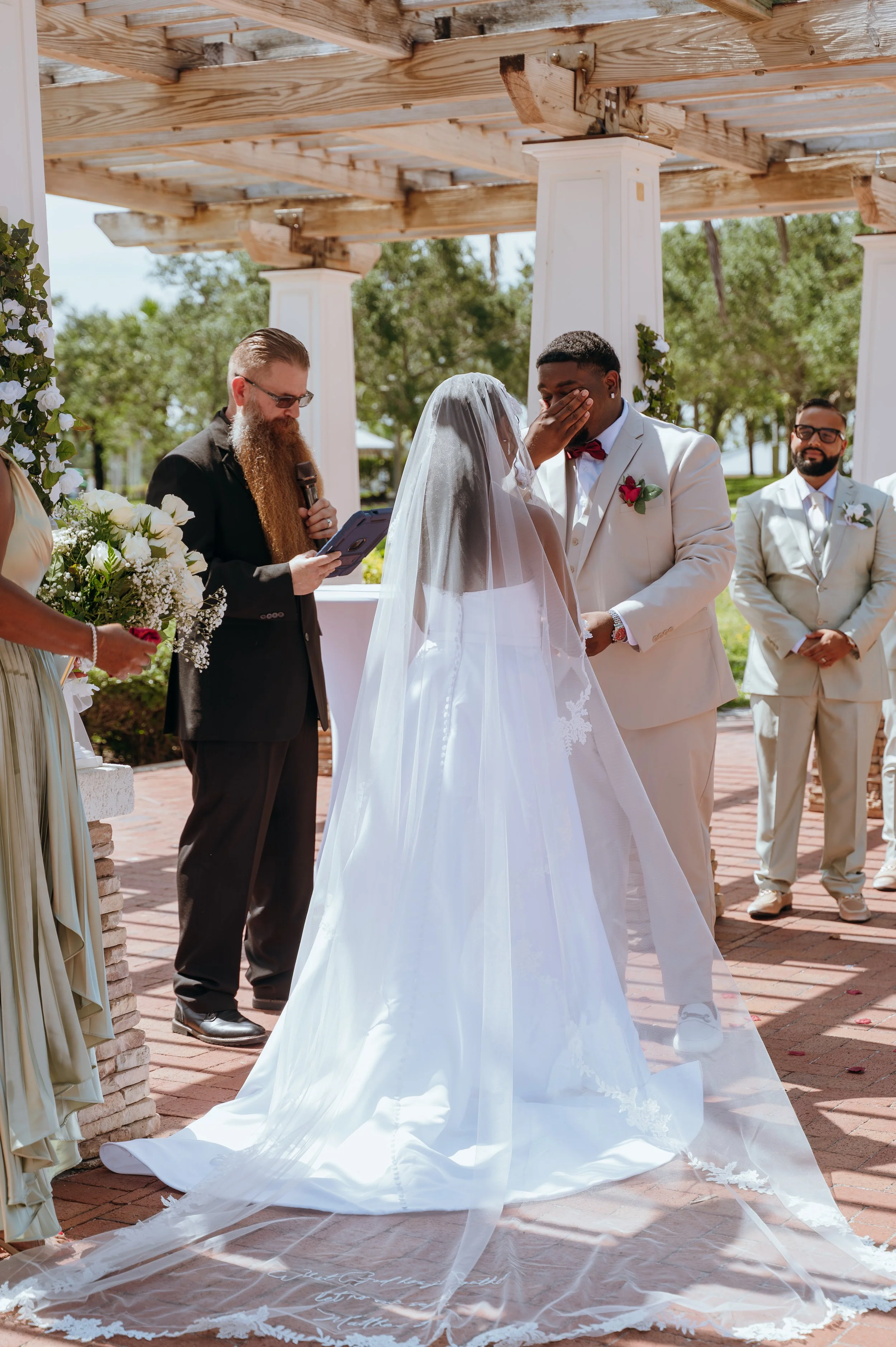 Groom Diego Waters wiping away tears while standing with Anndi during their wedding ceremony.