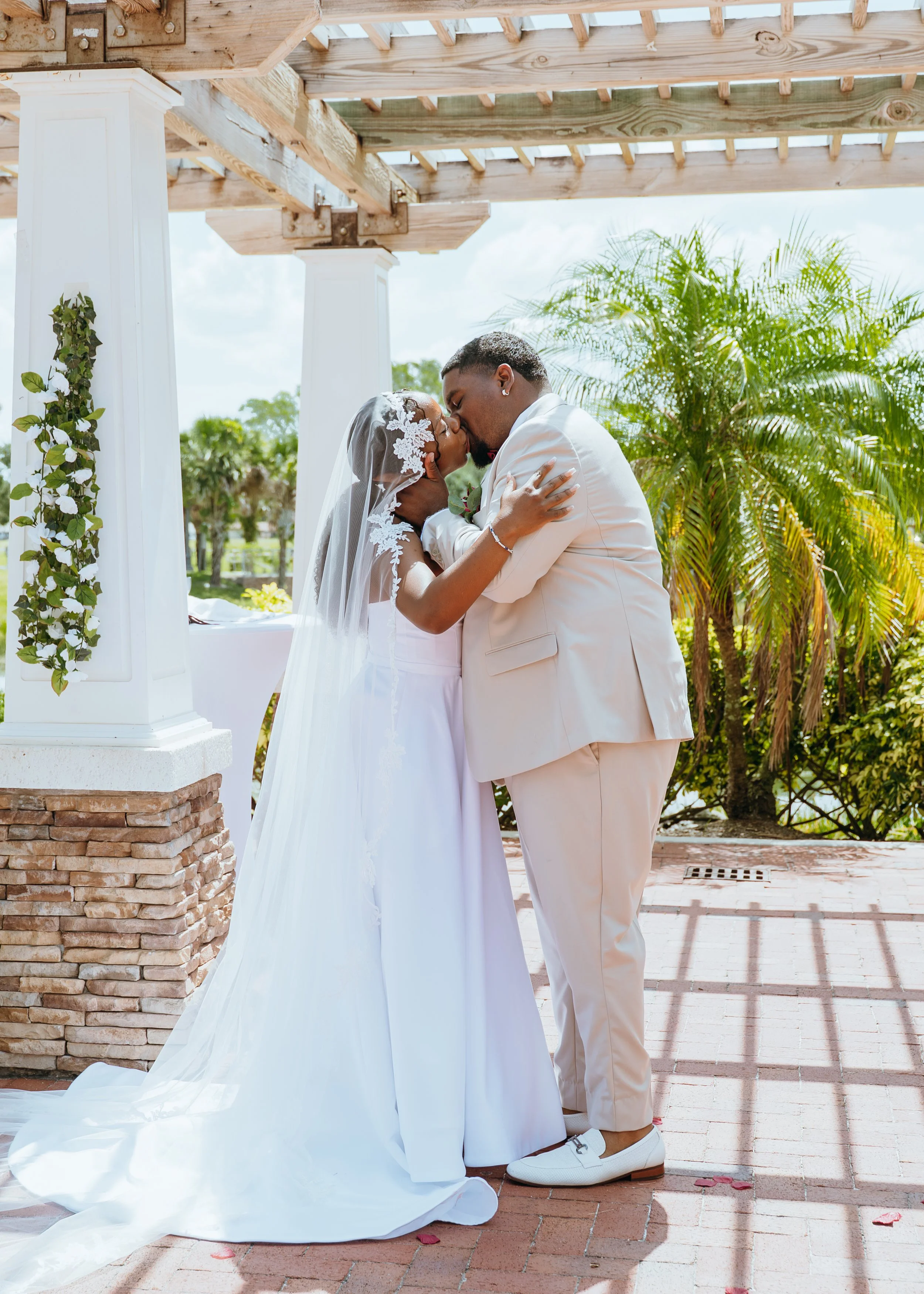 Anndi and Diego sharing their first kiss beneath the outdoor pergola at Royal Palm Beach Commons Park.