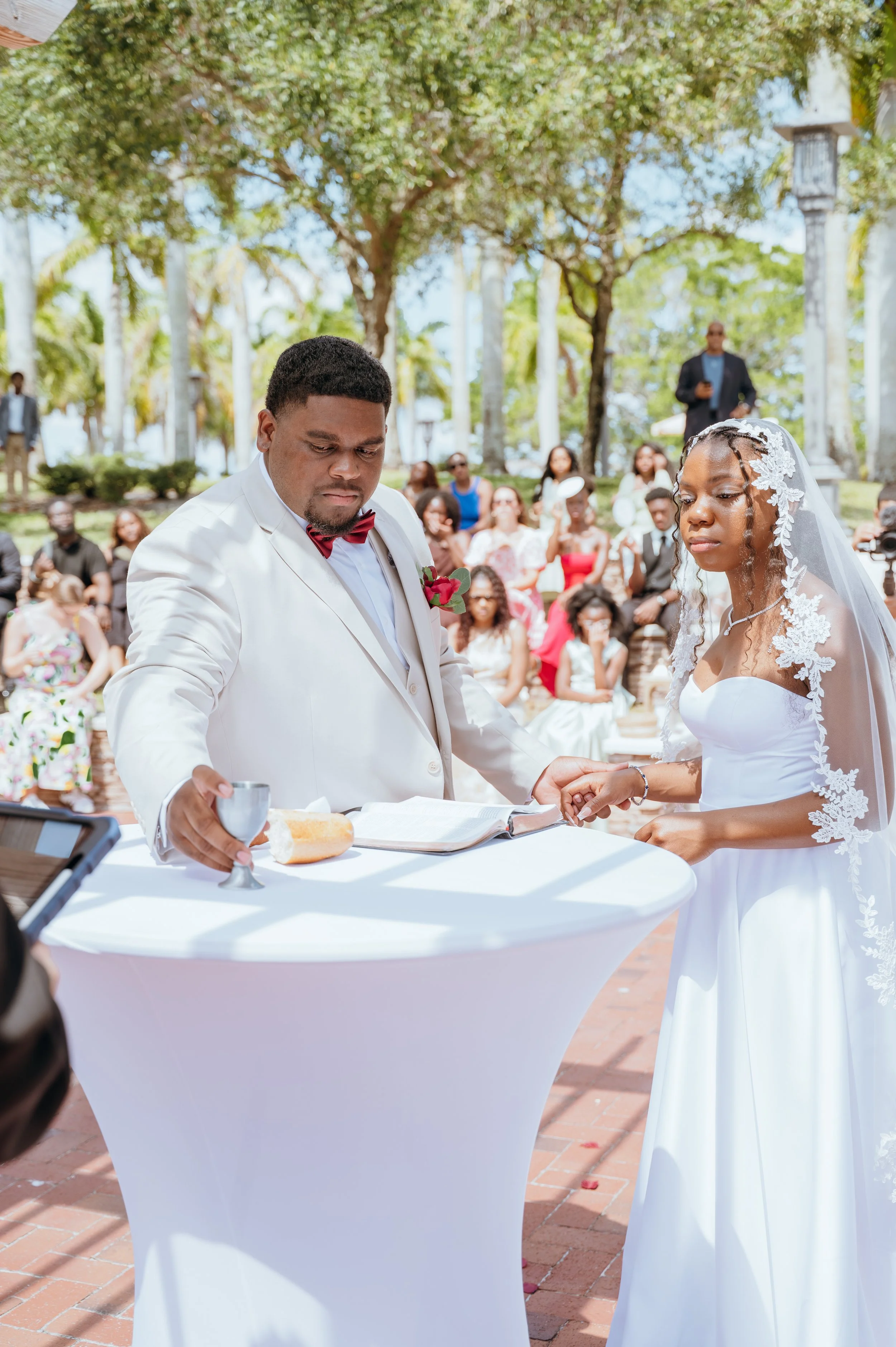 Anndi and Diego standing together at a communion table during their Christian wedding ceremony.
