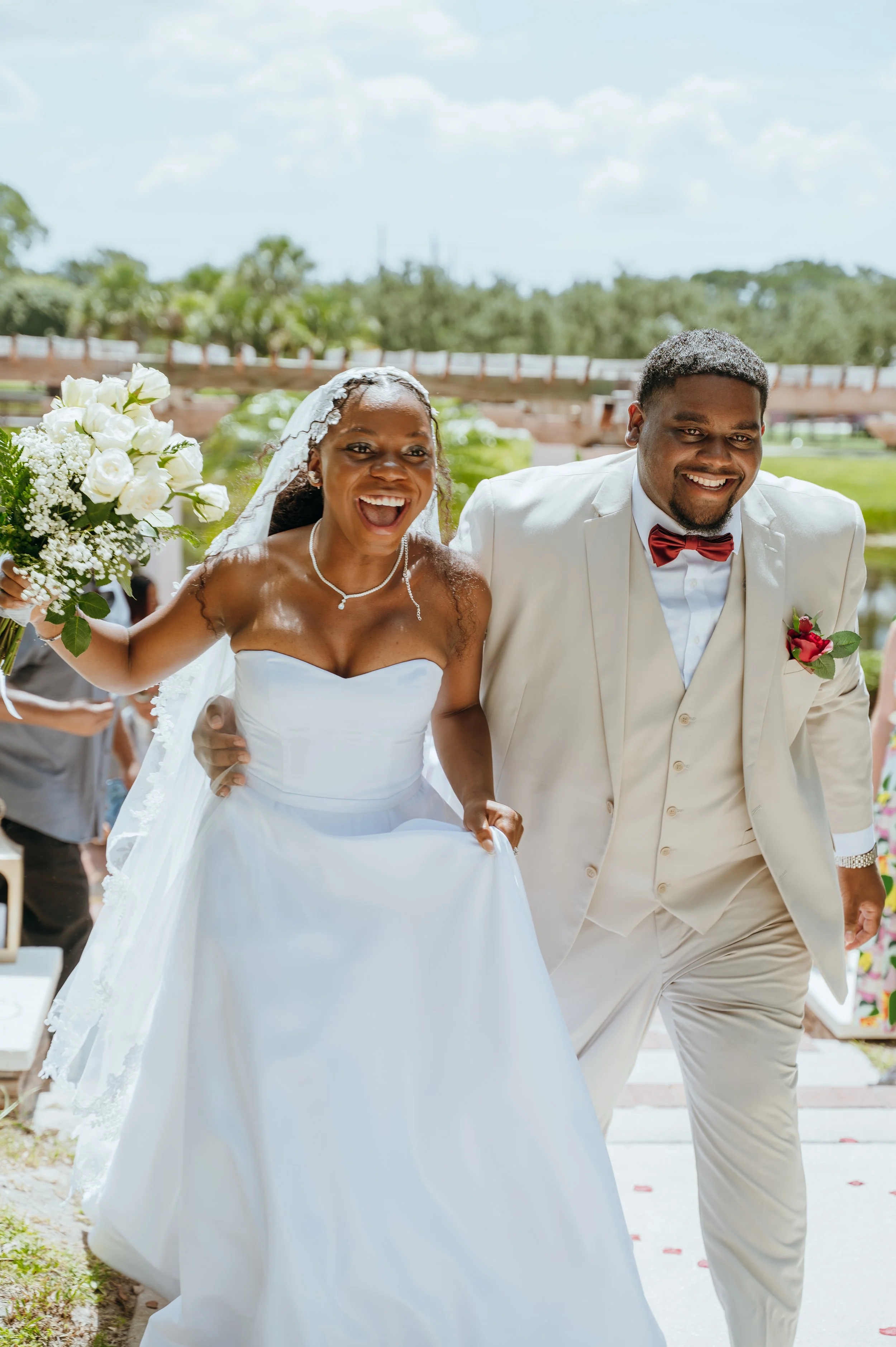 Newlyweds Anndi and Diego laughing together as they leave their Royal Palm Beach wedding ceremony.