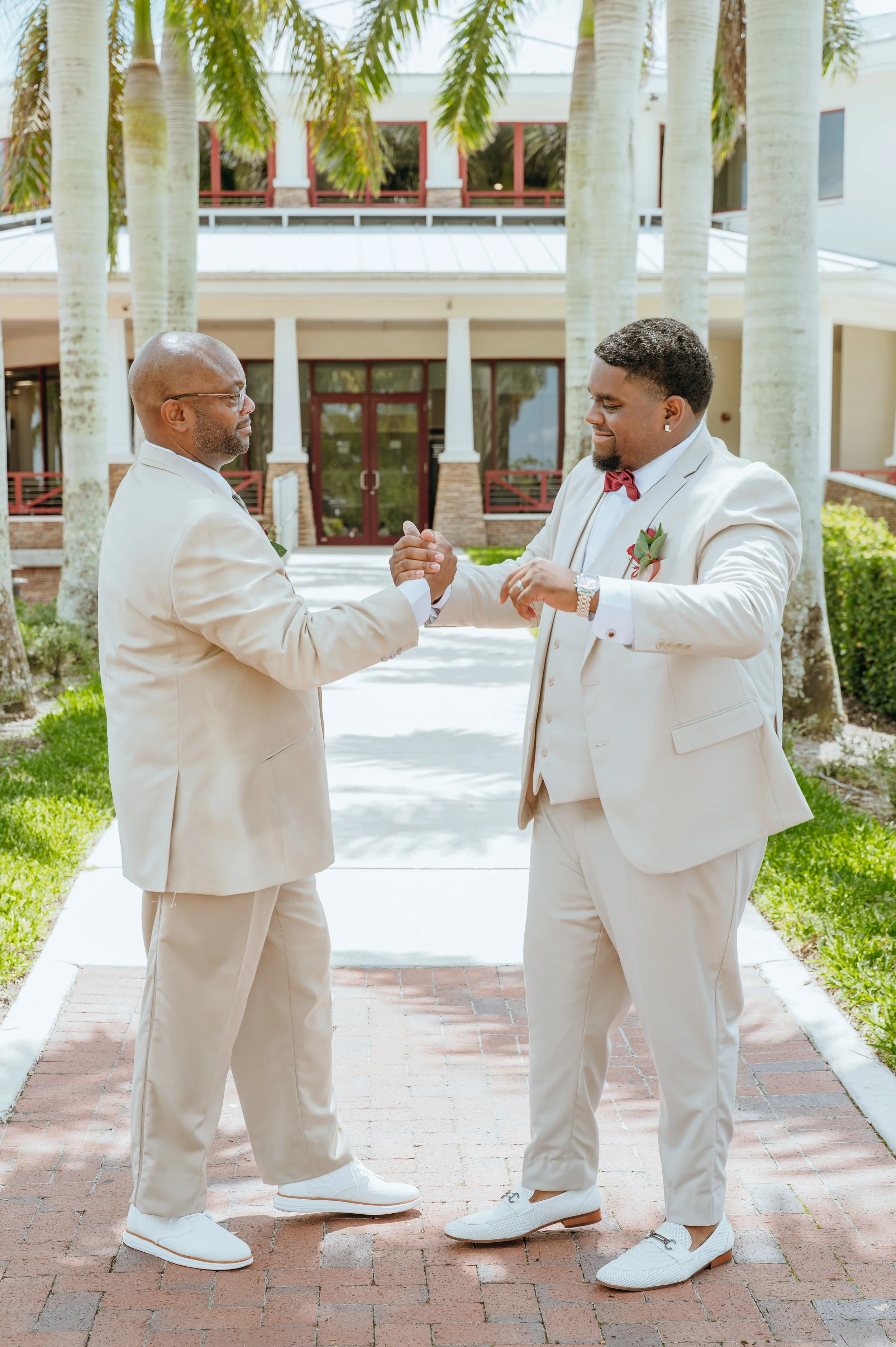 Diego Waters sharing a celebratory handshake with a loved one in a matching light-colored suit.