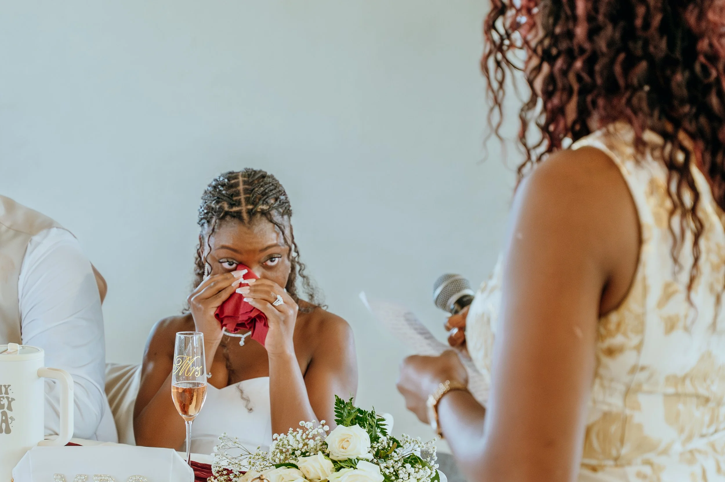 Bride Anndi wipes away tears while listening to heartfelt speeches at her wedding reception.
