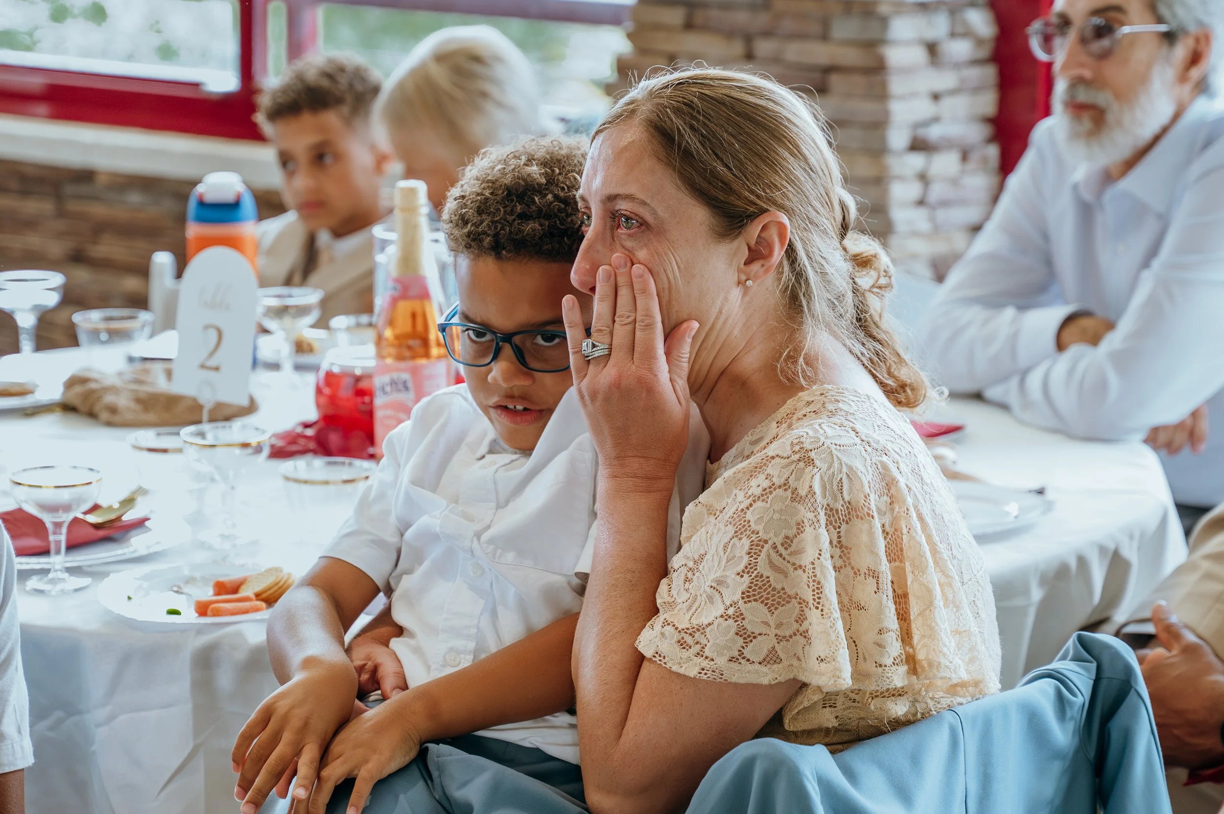A wedding guest wipes away a tear while listening to a heartfelt reception speech.