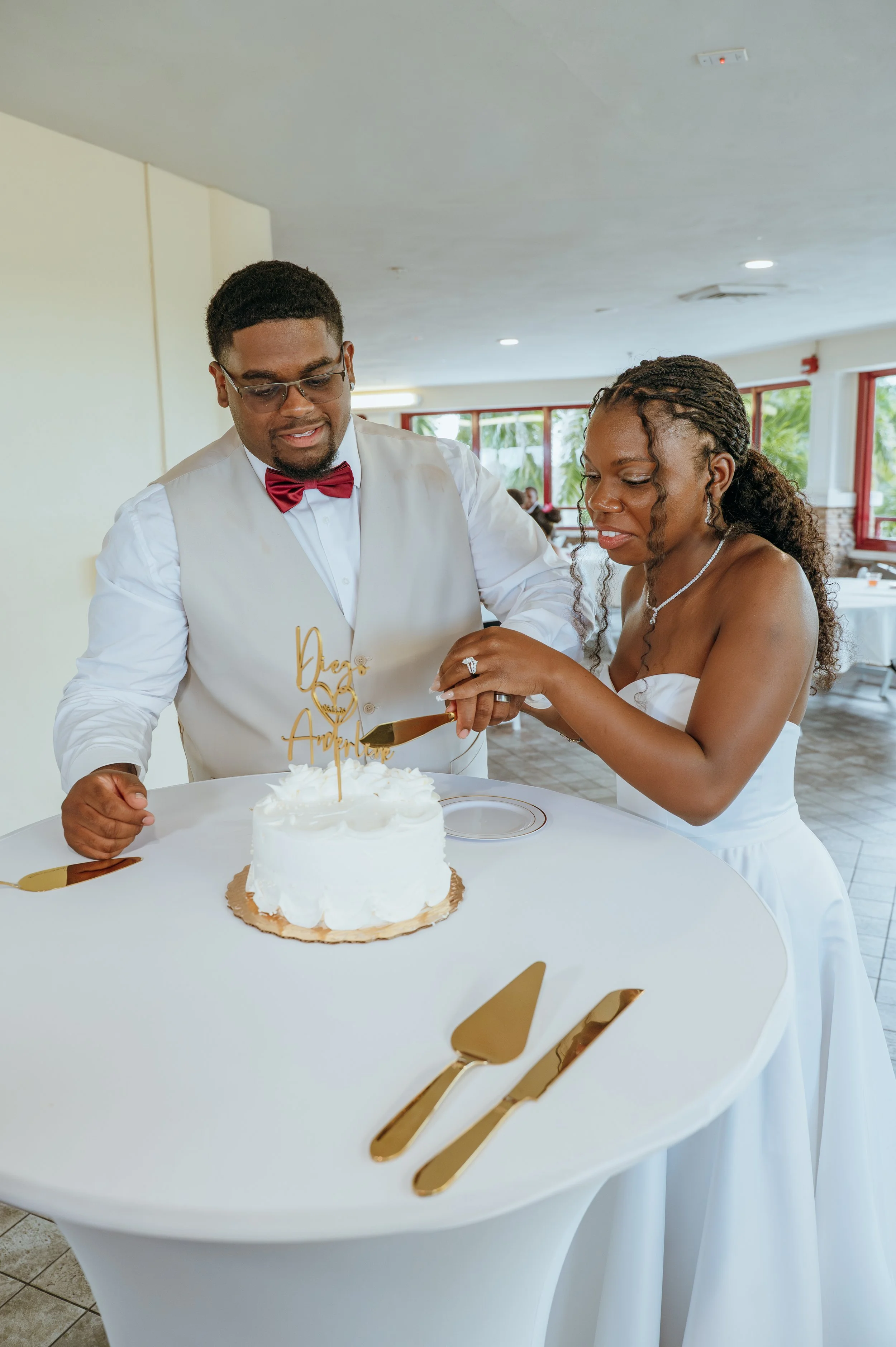 Anndi and Diego cut their white wedding cake together during their reception.