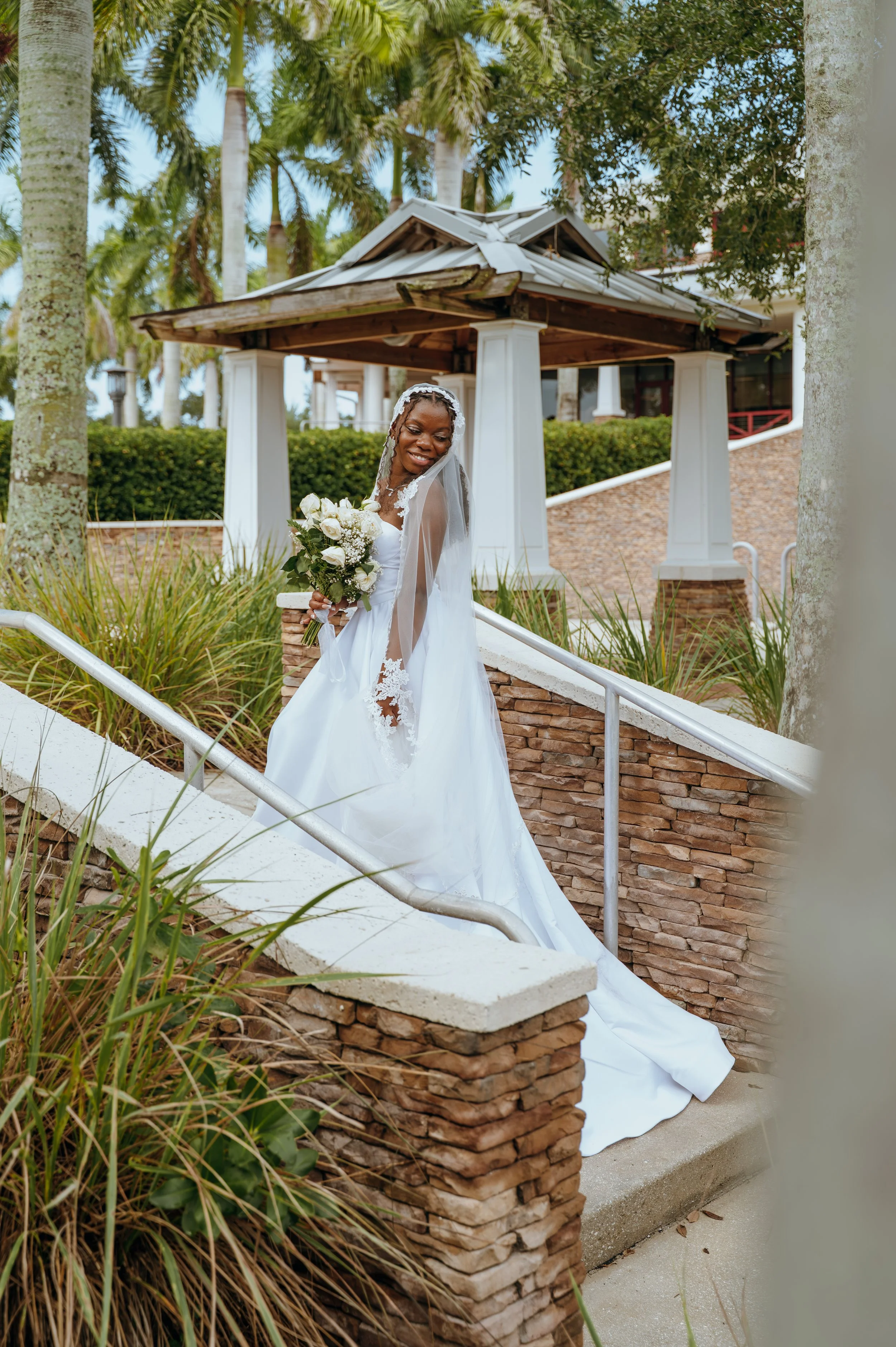 Anndi posing outdoors in her white wedding dress and lace-trimmed bridal veil.
