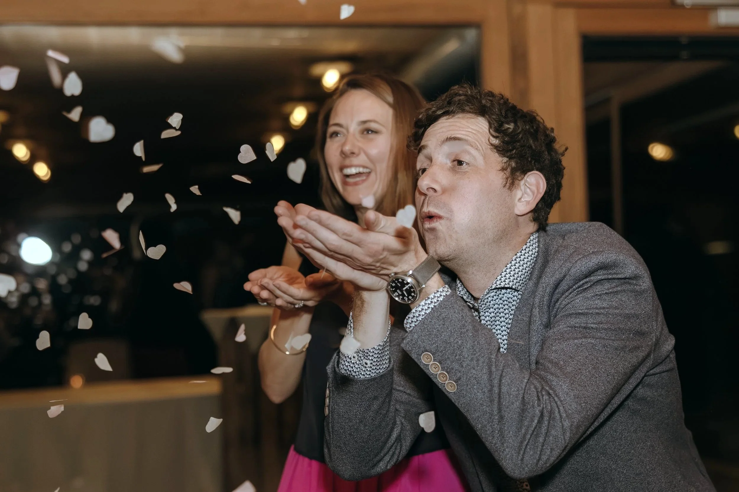 Wedding guests laughing as flower petals fly during the reception celebration in Switzerland