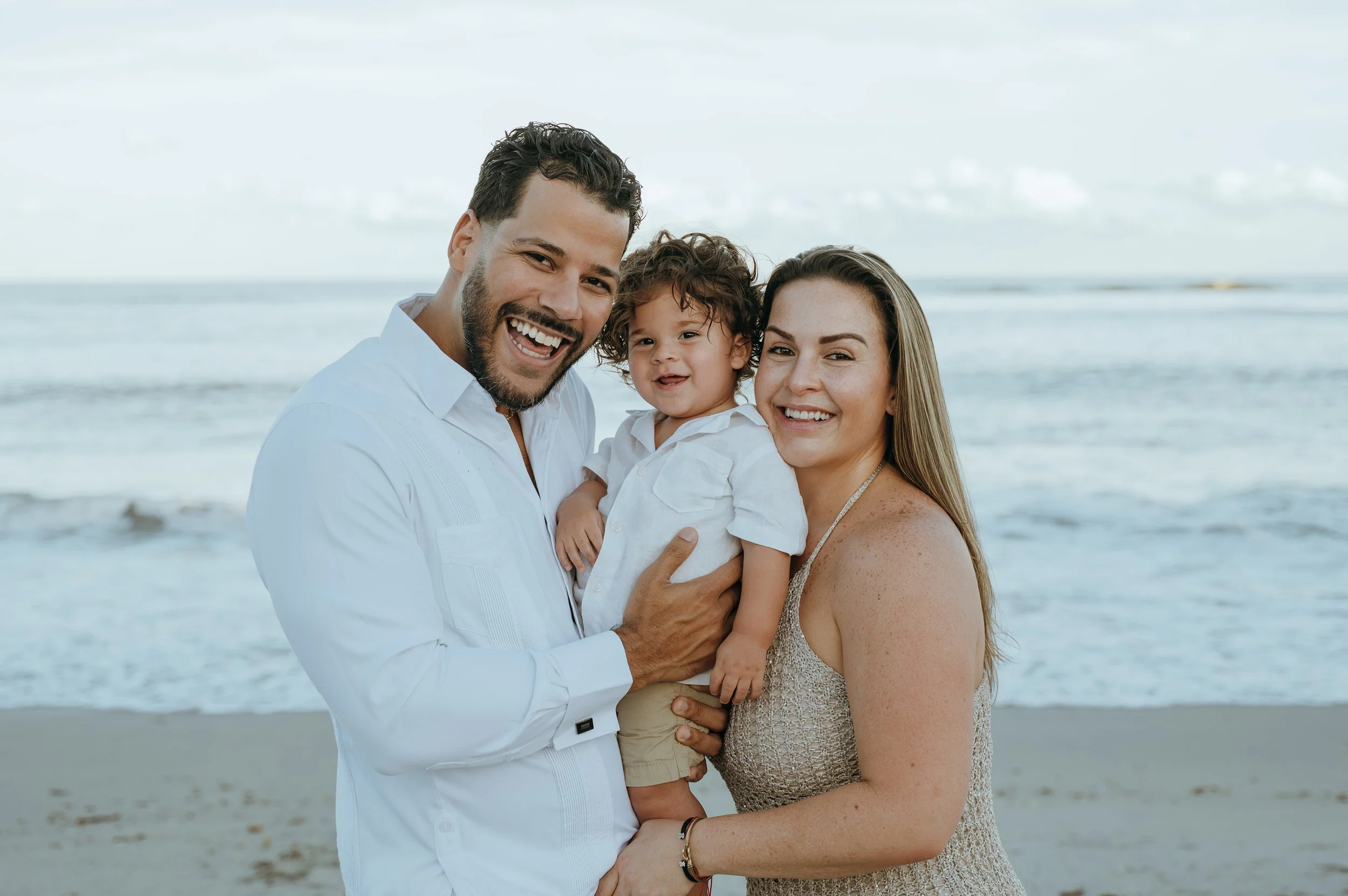 Parents smiling with their toddler during a family photography session at Boynton Inlet in Palm Beach County, Florida.