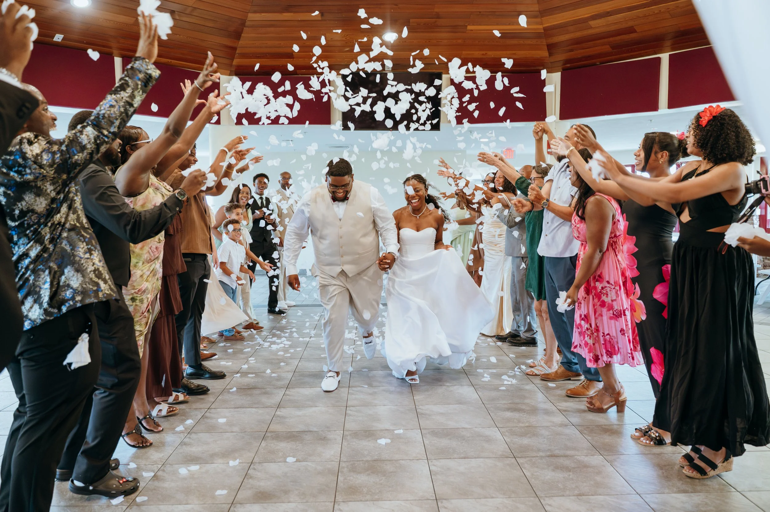 Newlyweds Anndi and Diego make their grand reception exit as guests shower them with white flower petals.