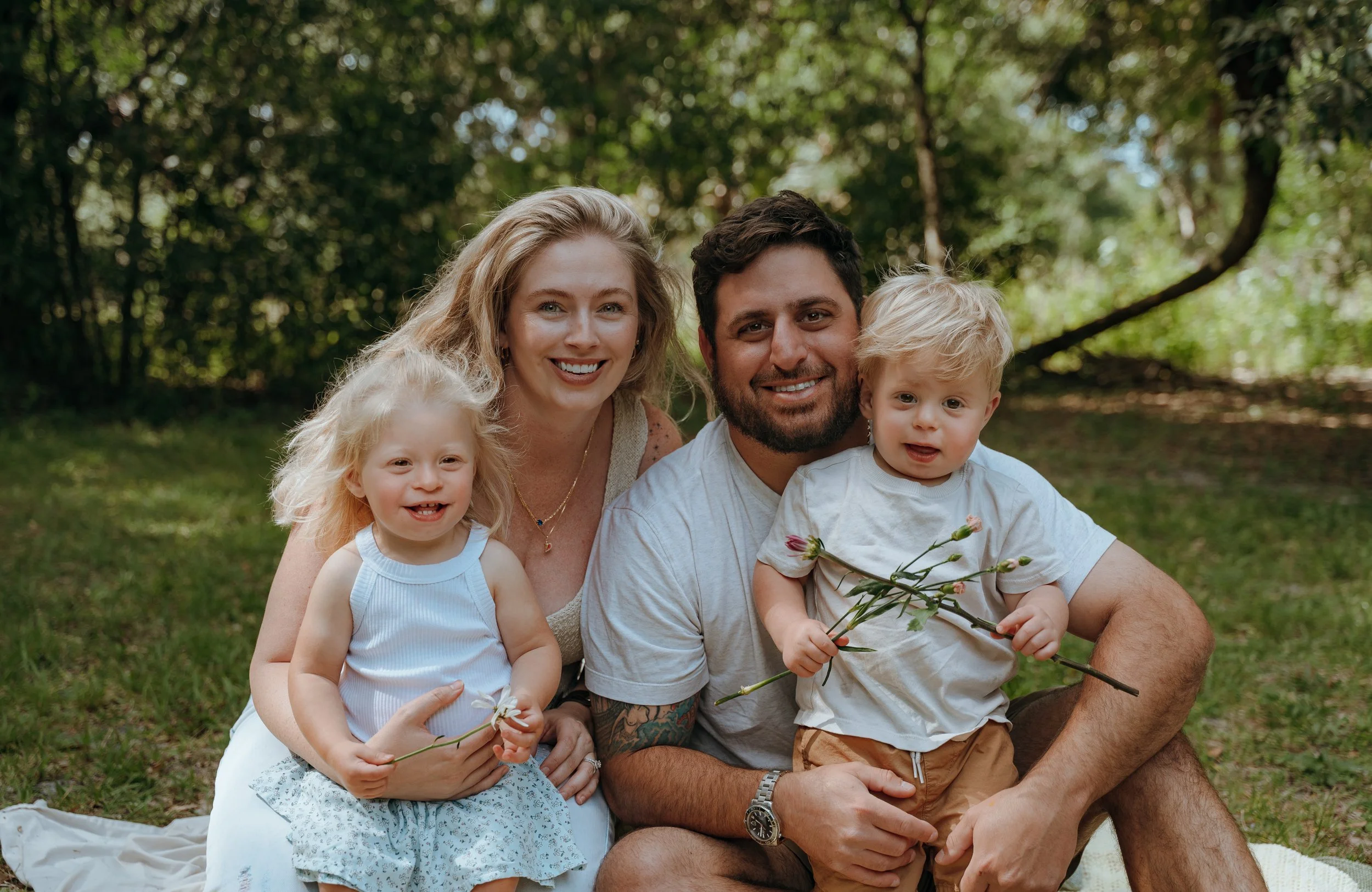 Family of four smiling together during a relaxed outdoor family photography session in Palm Beach County.