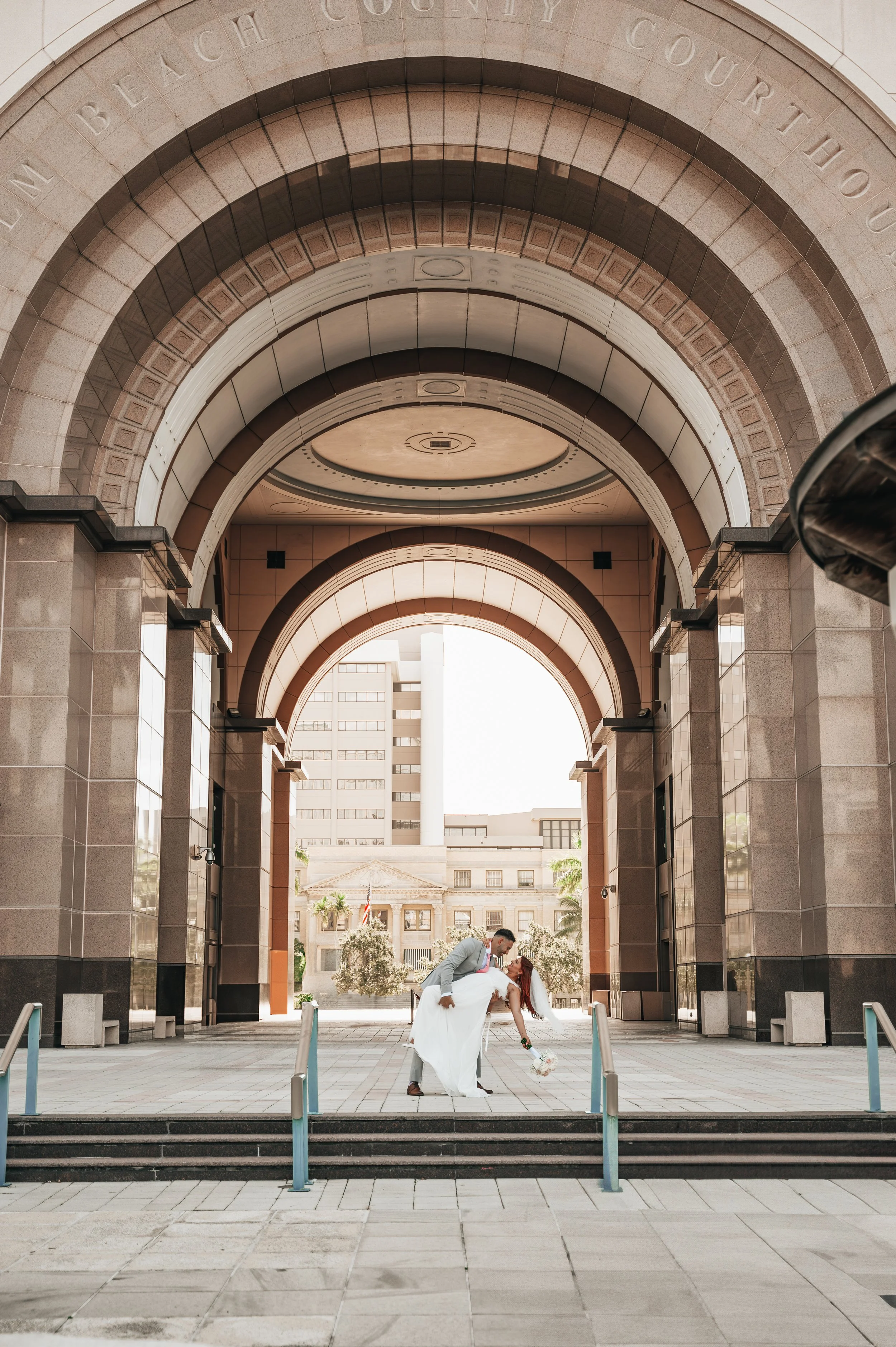 Newlyweds share a playful dip beneath the arches of the Palm Beach County Courthouse in West Palm Beach, Florida.