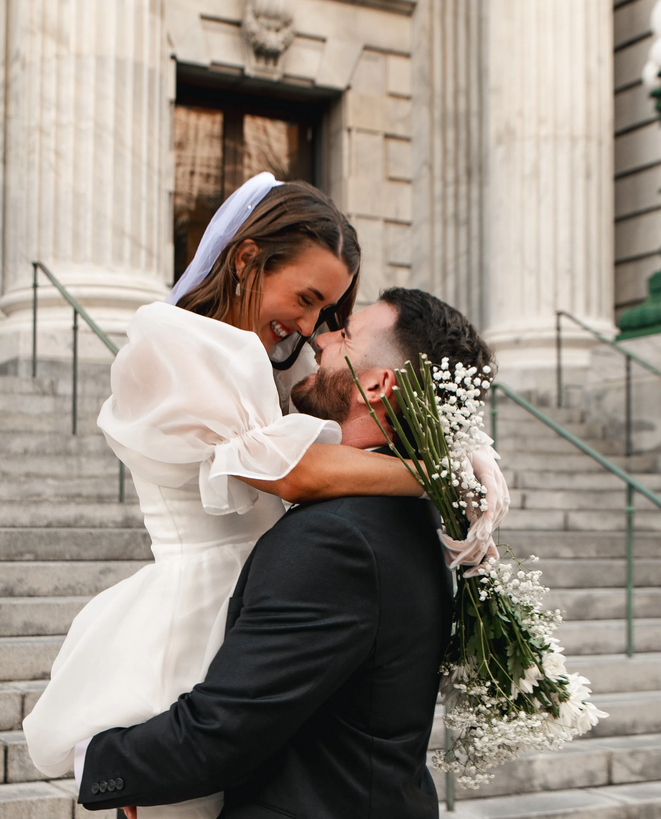 Joyful newlyweds embrace on the courthouse steps after their intimate Florida city hall wedding.