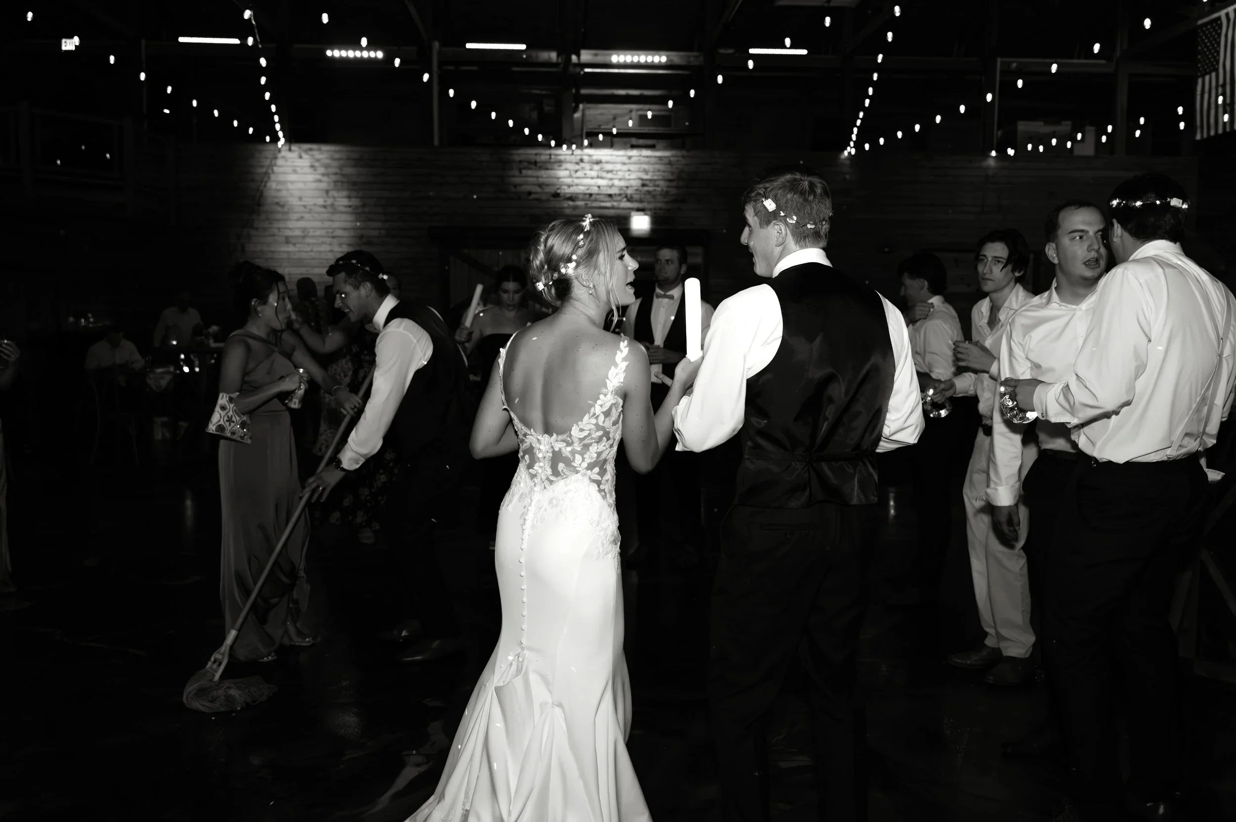 Black-and-white photograph of Sydney dancing among guests during her Gypsy Distillery wedding reception.