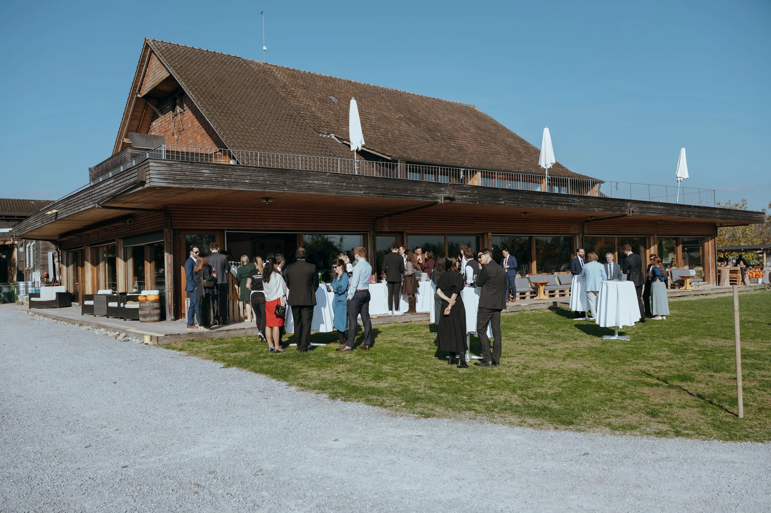 Wedding guests gathering for an outdoor cocktail hour overlooking the Swiss countryside at Jucker Farm