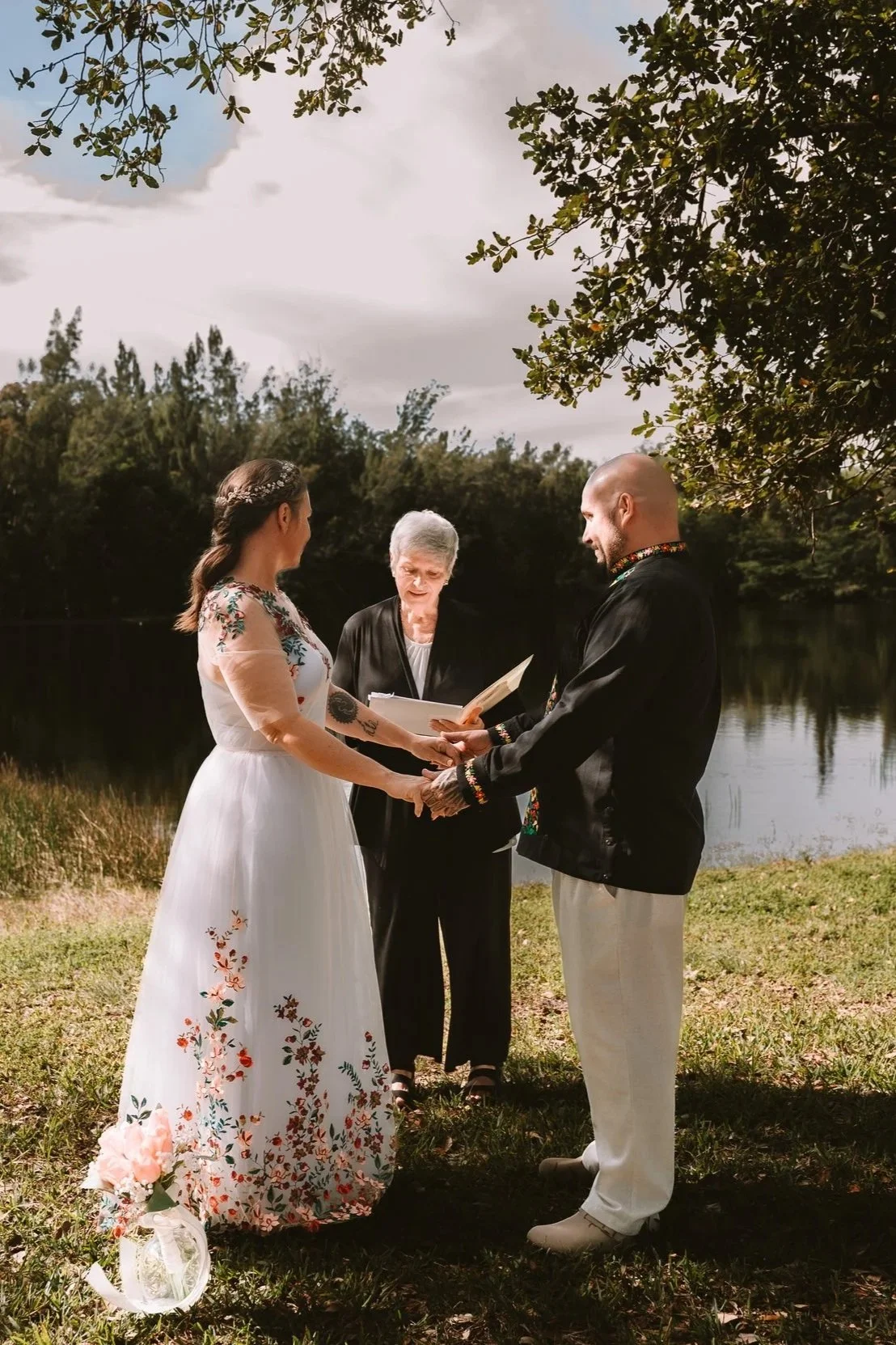 Couple exchanges vows beside the water during an intimate elopement at Tree Tops Park in Davie, Florida.