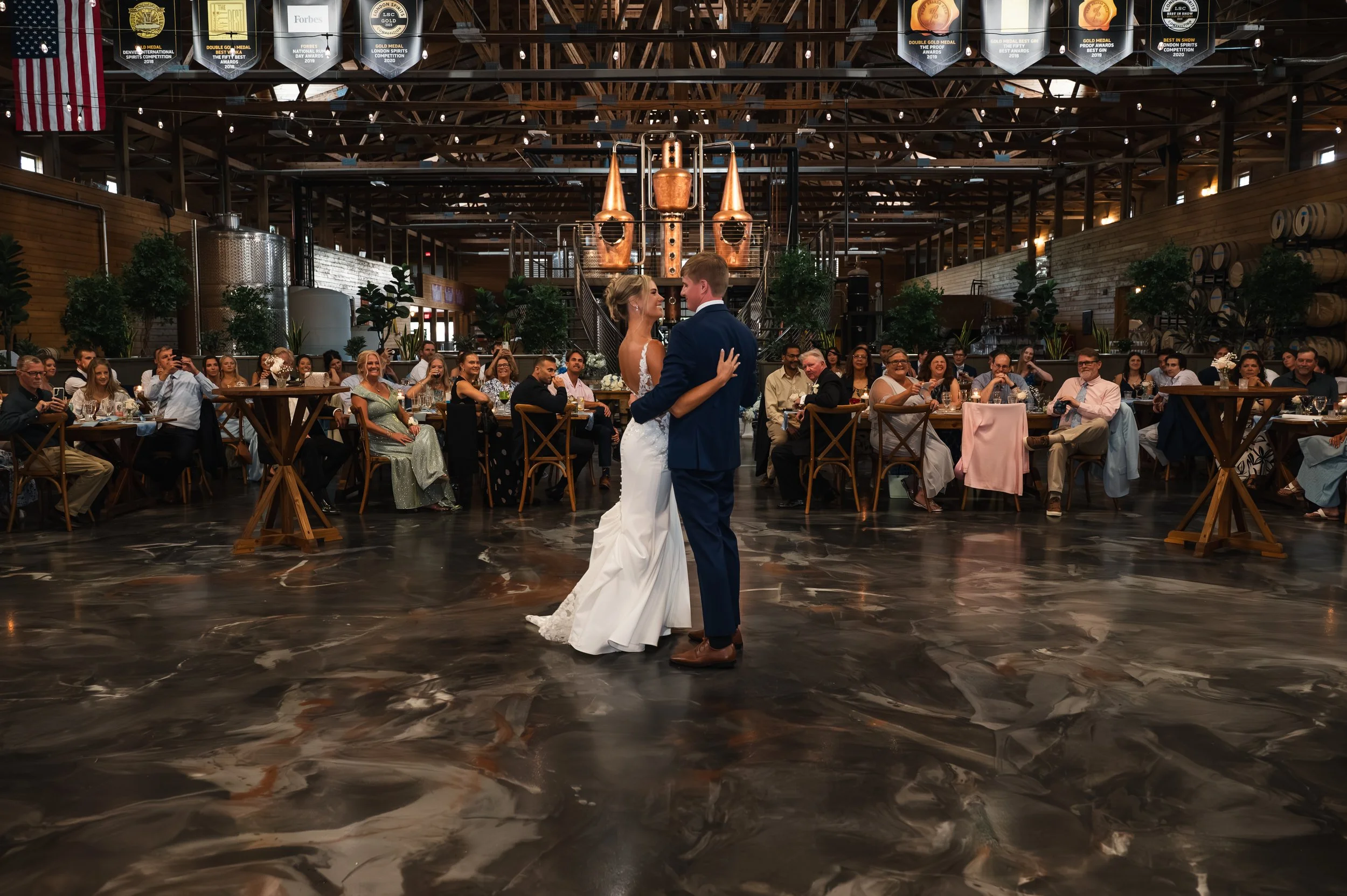 Sydney and Matt share their first dance surrounded by guests at Gypsy Distillery in Petoskey, Michigan
