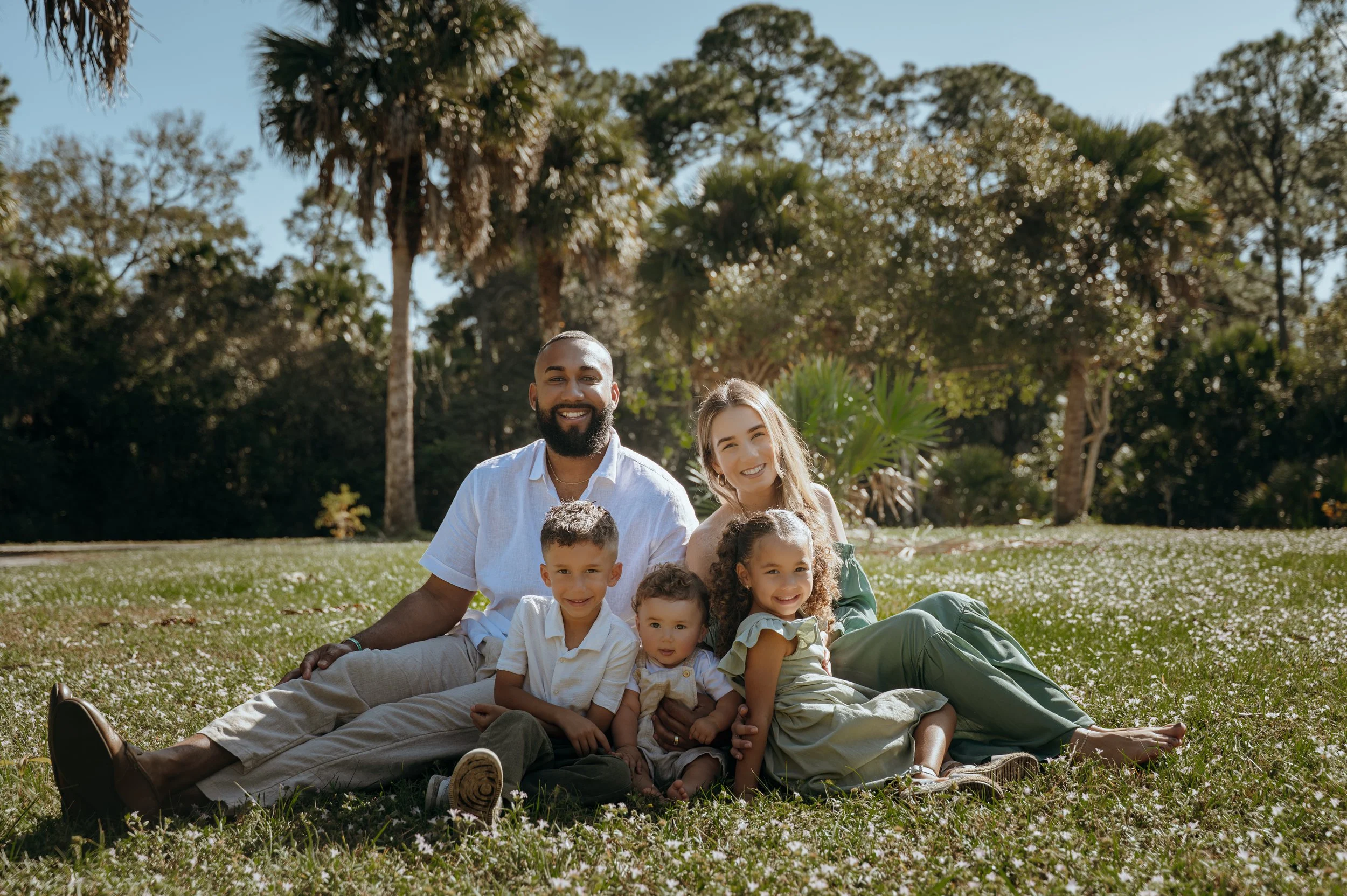 Parents seated with their three children during a relaxed outdoor family portrait session in Palm Beach County.