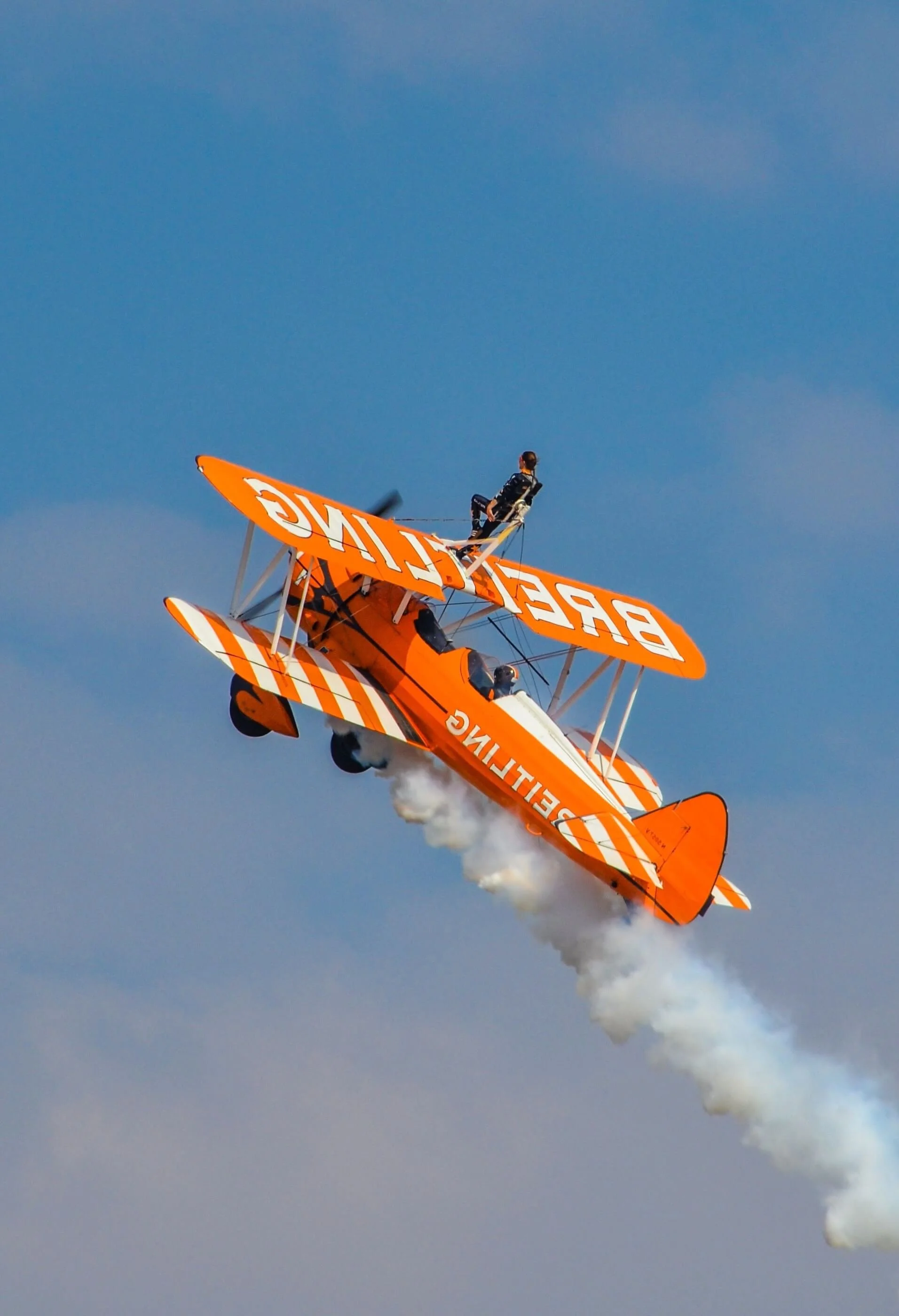 Wing walker on an orange biplane, illustrating risk and leadership during transformation.