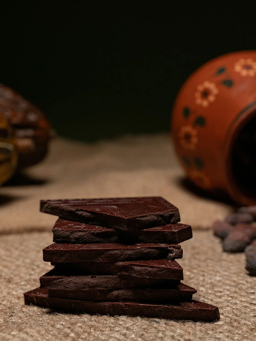 Broken pieces of Californio Chocolate Vanilla Bean 70% dark chocolate bar stacked on burlap
