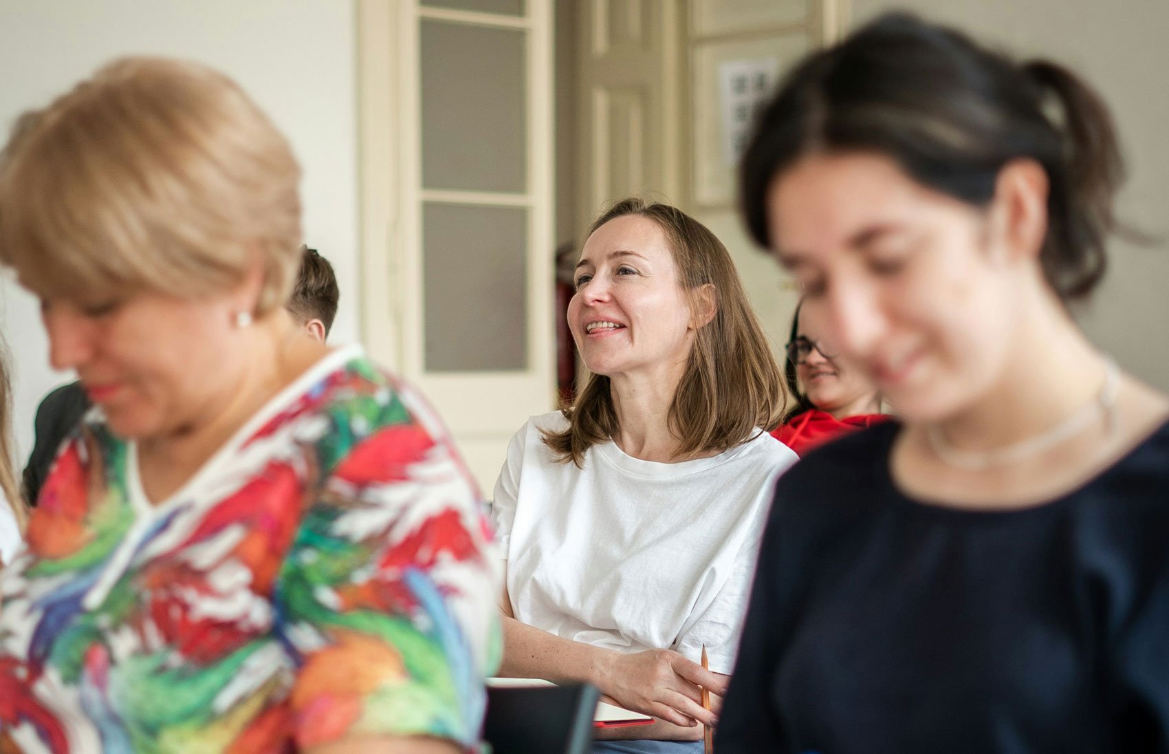 A woman smiles during a grief support group conversation as other members sit around her