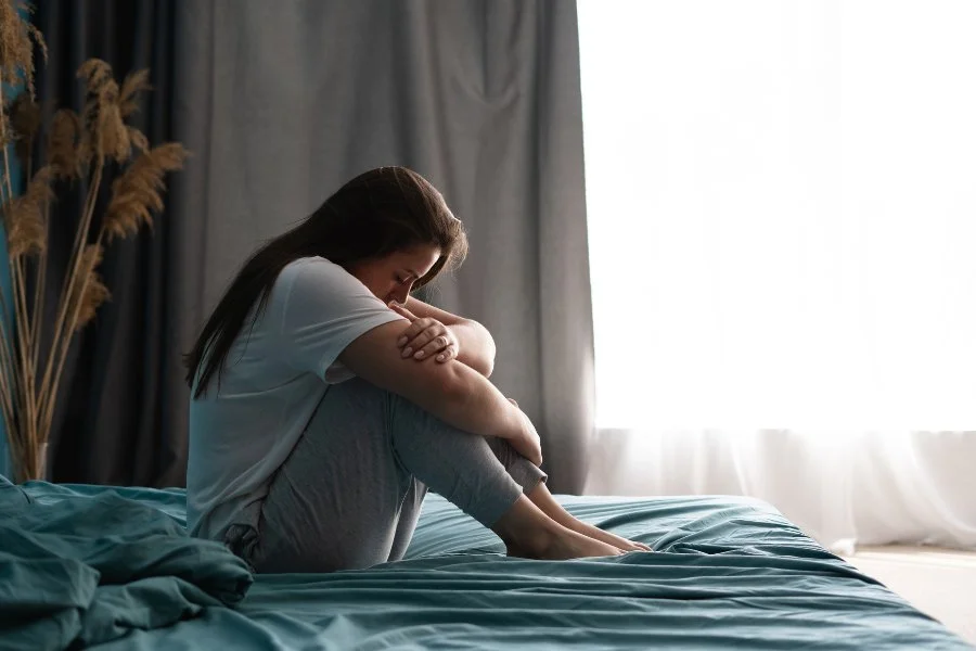 Woman on bed overwhelmed by grief, needing therapy in Tucson