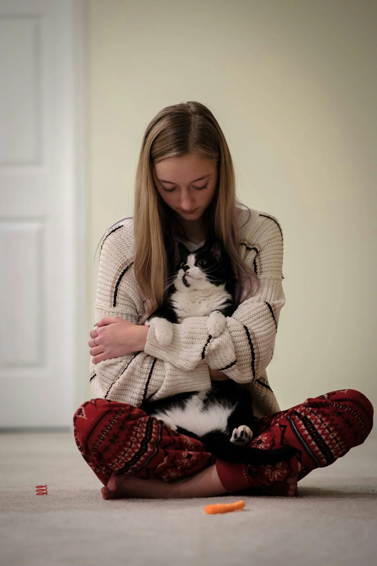 Woman lovingly hugging her cat while they play on the floor.