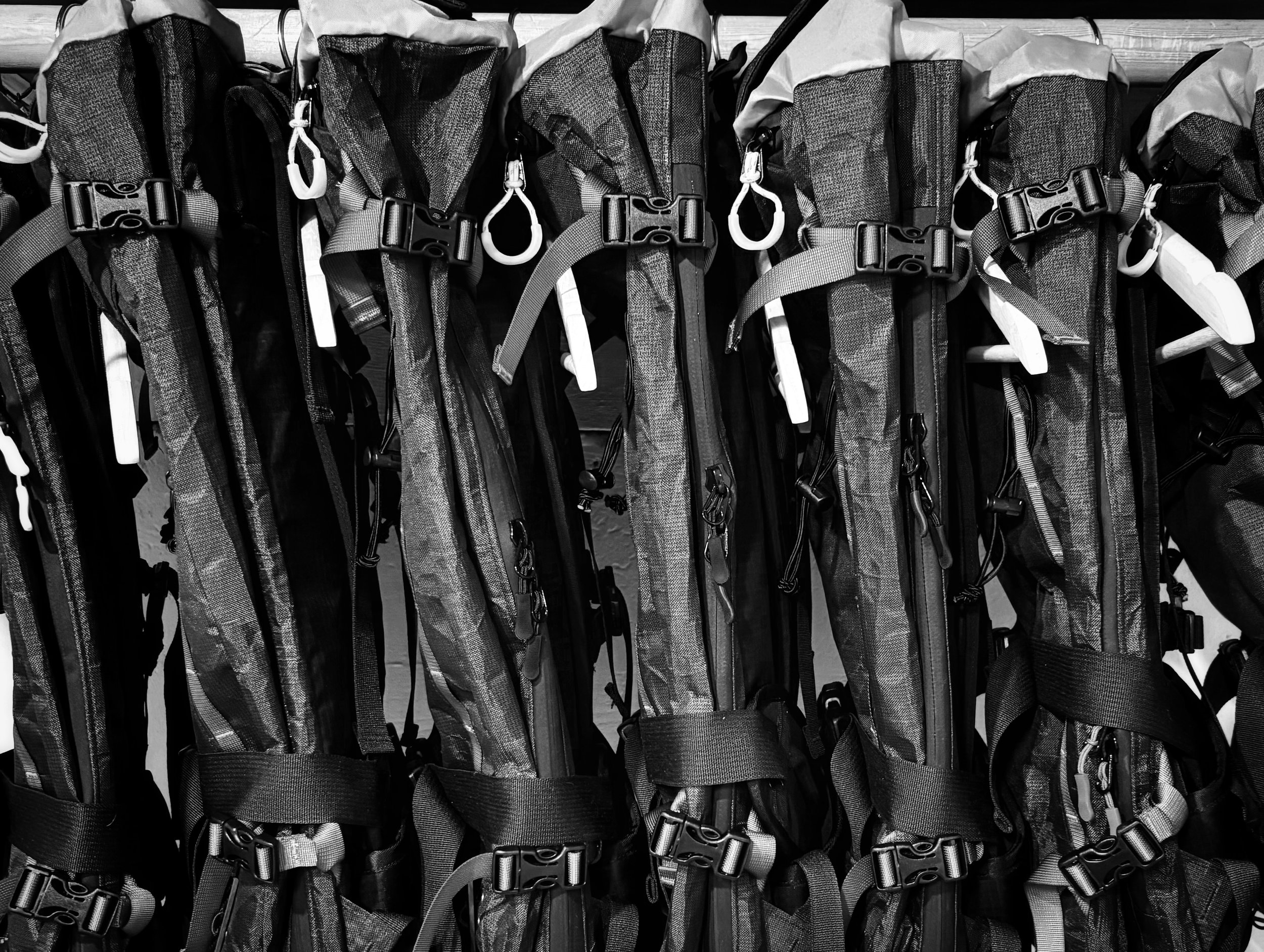 Multiple black and gray outdoor backpacks hanging on a store display.
