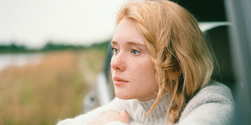 Woman looking out window of a car pensively