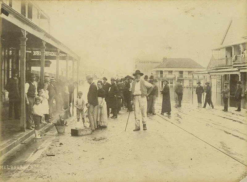 An old photos of a crowd of people on a muddy street.