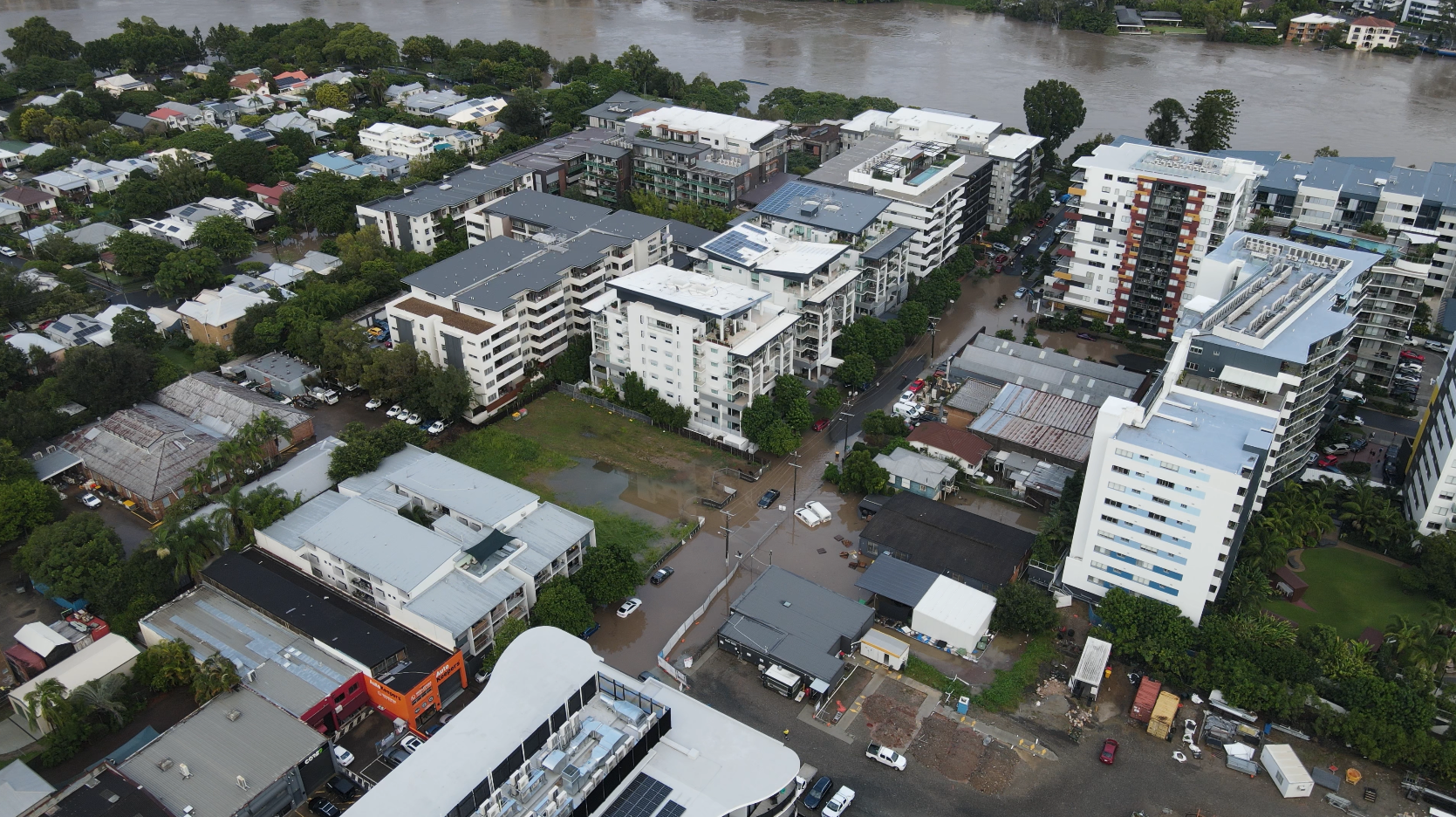 An aerial view of riverside apartment blocks on flooded streets.