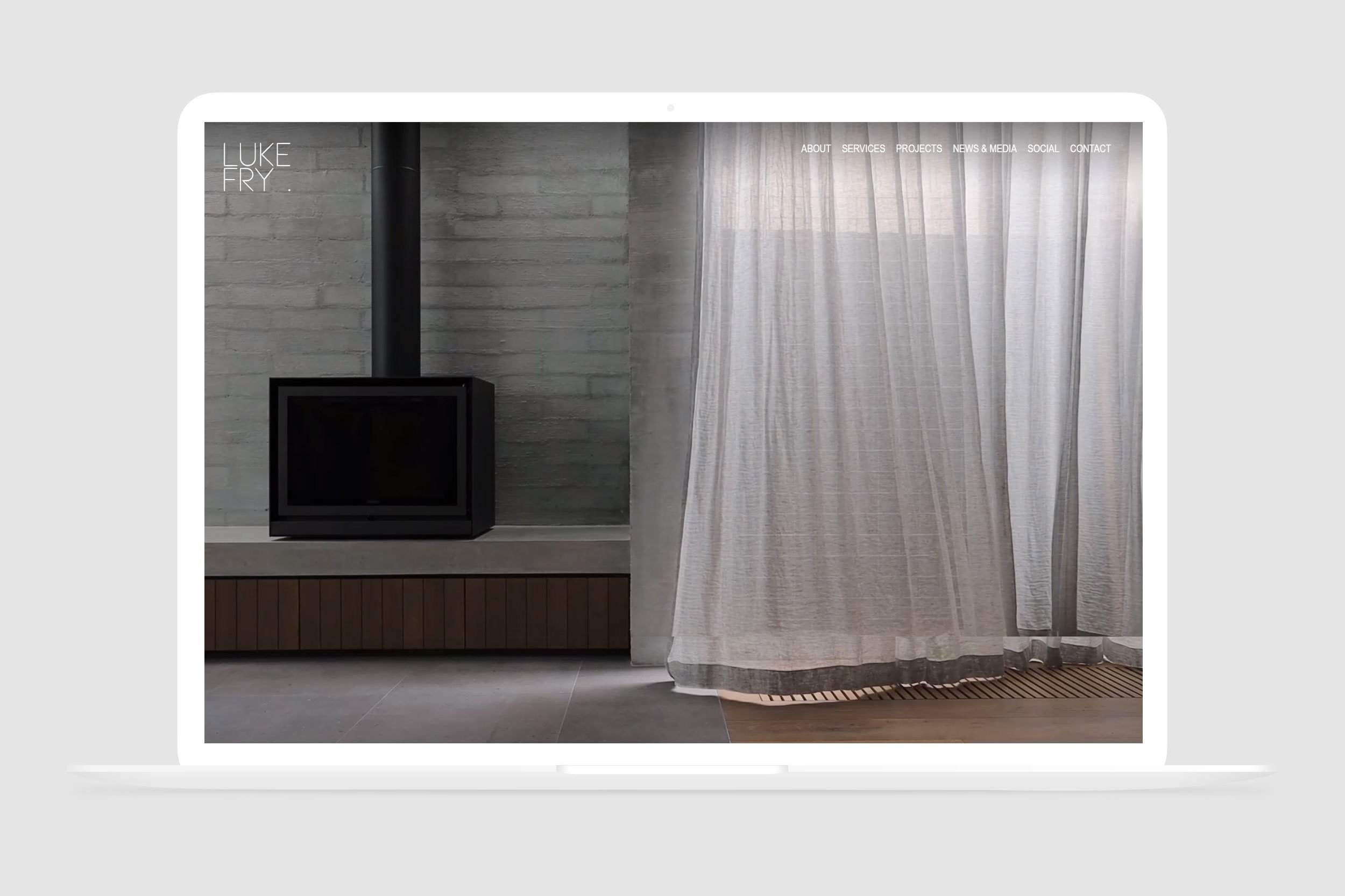 Website home page with full screen video, showing a curtain gently blowing in a light breeze inside a beautifully designed home.