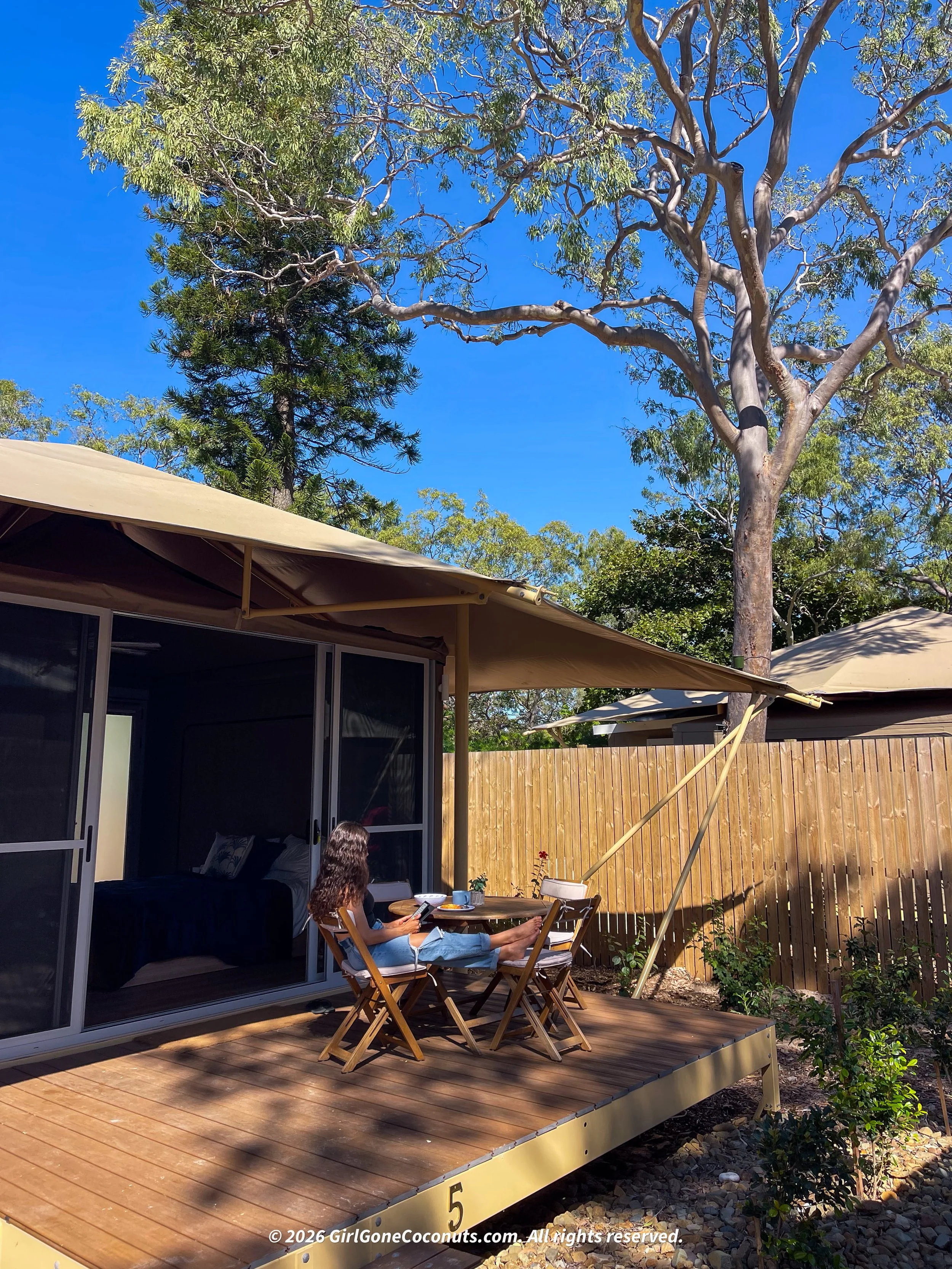 Traveler sitting outside reading her Kindle at her Glamping Tent at Great Keppel Island Hideaway.